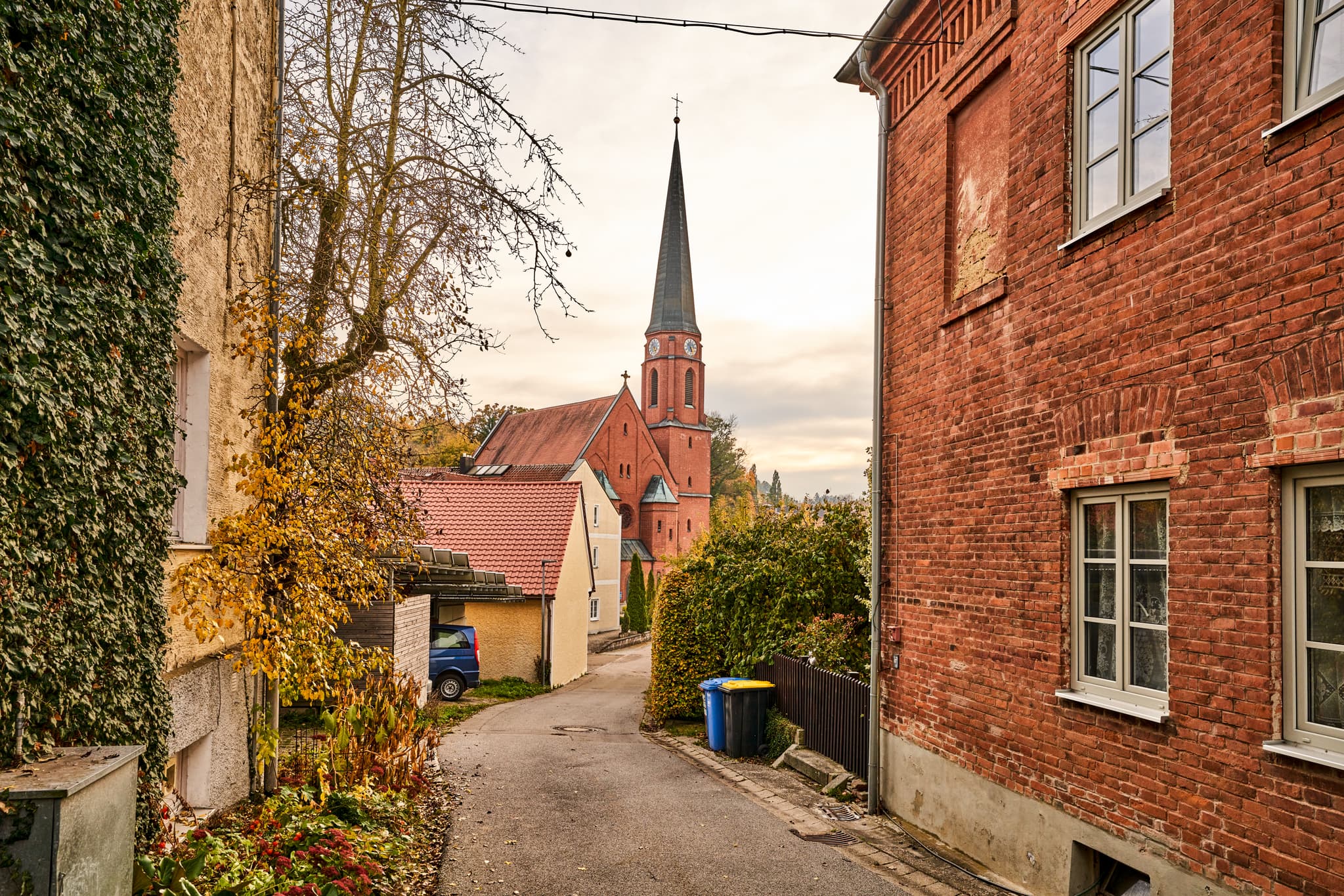 Alte Schule Hörniweg, Schönau, Rottal-Inn, Niederbayern - Blick von der Alte Schule Hörniweg in Schönau, Landkreis Rottal-Inn, Niederbayern, Deutschland. Gasse mit Backsteinhaus und  Kirche im herbstlichen Holzland.