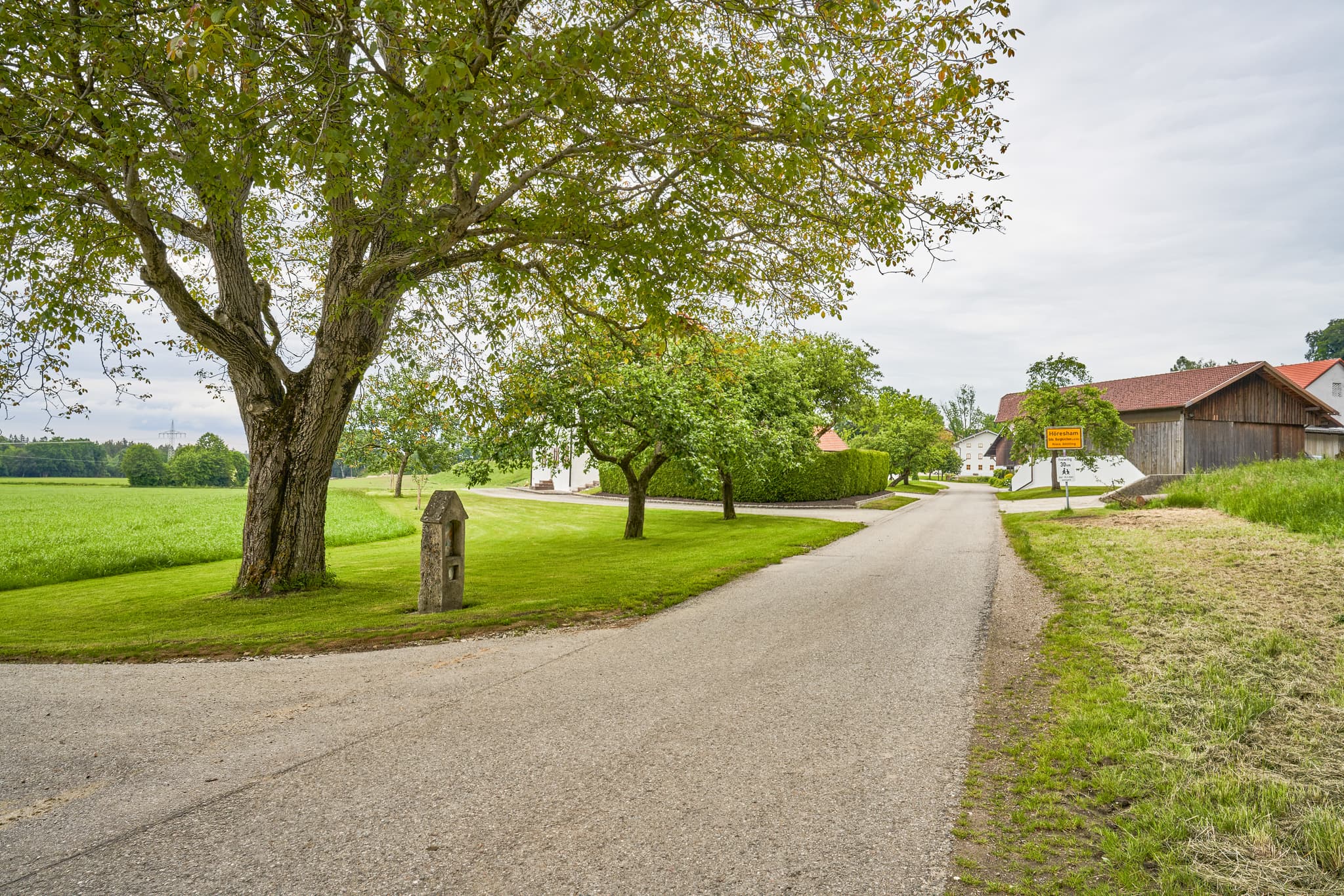 Alter Bildstock Höresham, Altötting, Oberbayern, Inn-Salzach - Alter Bildstock in Höresham, Burgkirchen, Altötting. Ländliche Szene in Oberbayern, Inn-Salzach, Deutschland. Zeigt Feldweg, grüne Wiesen, Bäume, Gebäude.