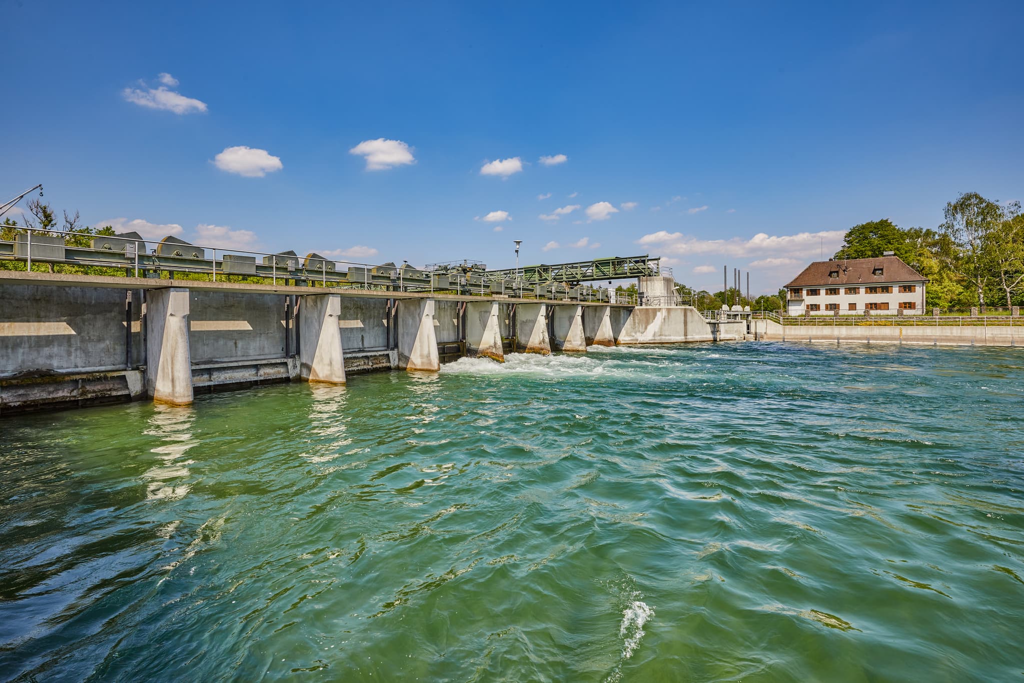 Alz Radweg, Burgkirchen-Hirten, Oberbayern, Inn-Salzach - Wehranlage Alz, Burgkirchen-Hirten, Burgkirchen, Altötting, Oberbayern. Klares Wasser prägt Inn-Salzach, Deutschland. Betriebsgebäude, Uferbäume, blauer Himmel.