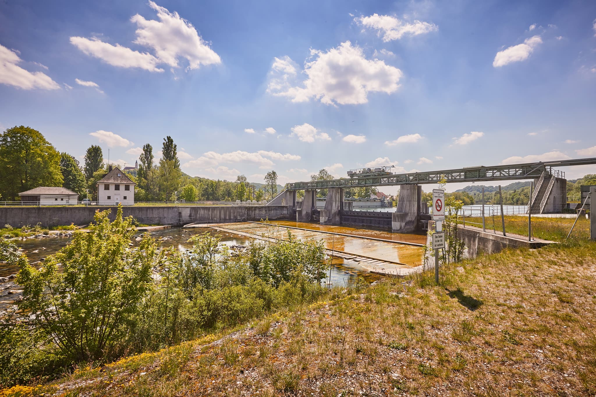 Alz Radweg in Burgkirchen-Hirten, Oberbayern, Inn-Salzach - Stauwehr am Fluss in Burgkirchen-Hirten, Burgkirchen, Altötting, Oberbayern. Grüne Landschaft der Inn-Salzach Region in Deutschland unter blauem Himmel.