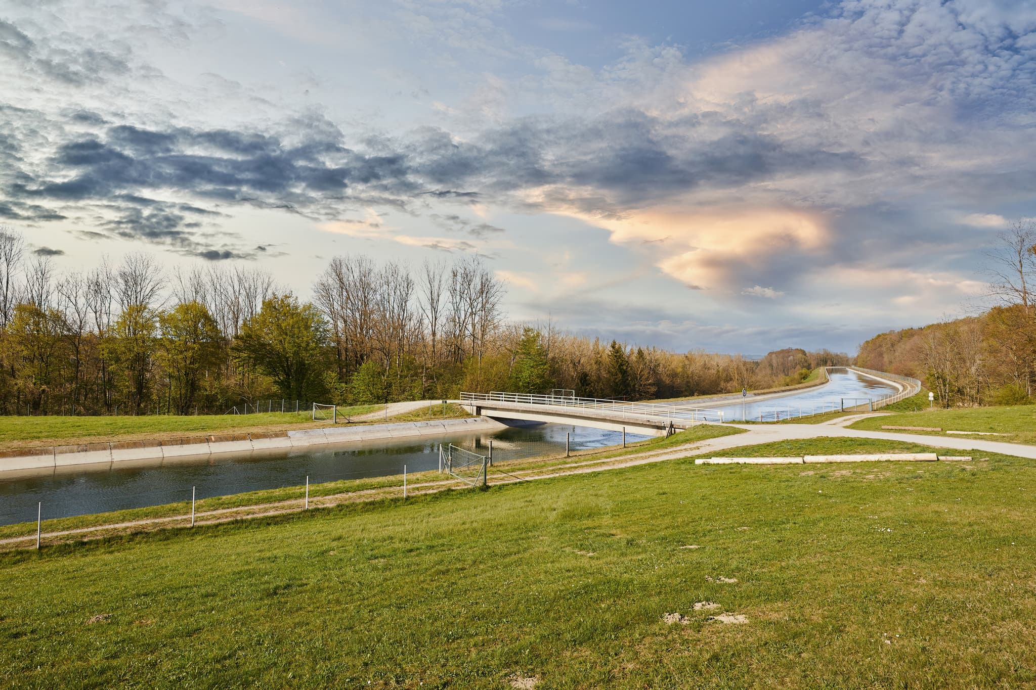 Alzkanal in Burgkirchen, Altötting, Oberbayern, Inn-Salzach - Der Alzkanal in Burgkirchen, Altötting, Oberbayern. Motiv: Kanal mit Brücke, grüne Wiesen, Bäume unter Wolkenhimmel.