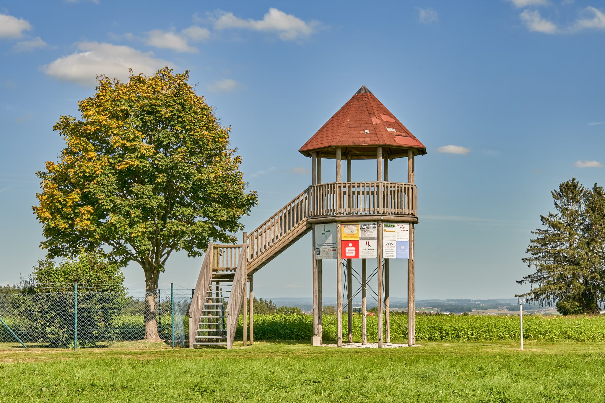 Aussichtsturm Schnaitsee, Landkreis Traunstein, Oberbayern - Aussichtsturm in Schnaitsee, Landkreis Traunstein, Oberbayern. Motiv: Turm auf Wiese mit Baum, blauer Himmel in der Region Chiemgau, Deutschland.