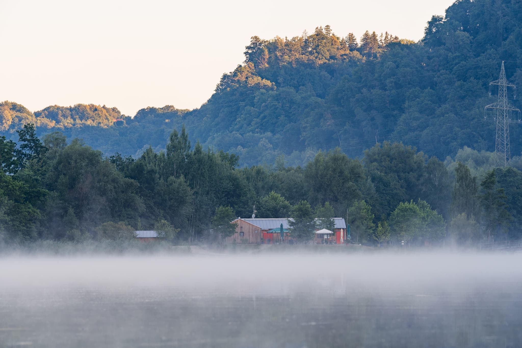 Badesee Kiosk am Morgen in Marktl, Altötting, Oberbayern - Badesee in Marktl, Altötting, Oberbayern, Deutschland: Morgennebel über dem See. Klare Sicht auf die Landschaft der Region Inn-Salzach.