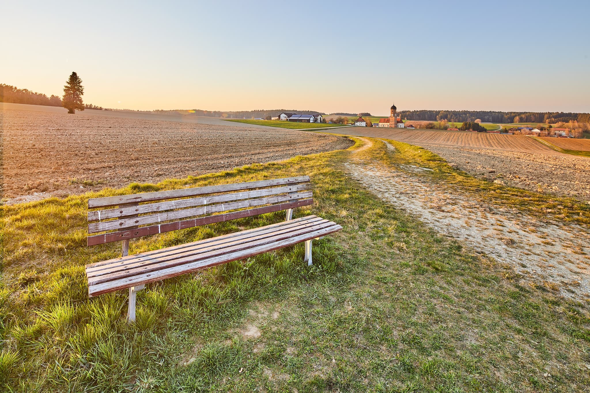 Bank mit Aussicht, Landschaft Martinskirchen, Rogglfing - Weite Landschaft mit Bank und Dorf im Hintergrund bei Martinskirchen Rogglfing, Wurmannsquick, Landkreis Rottal-Inn, Niederbayern, Deutschland.