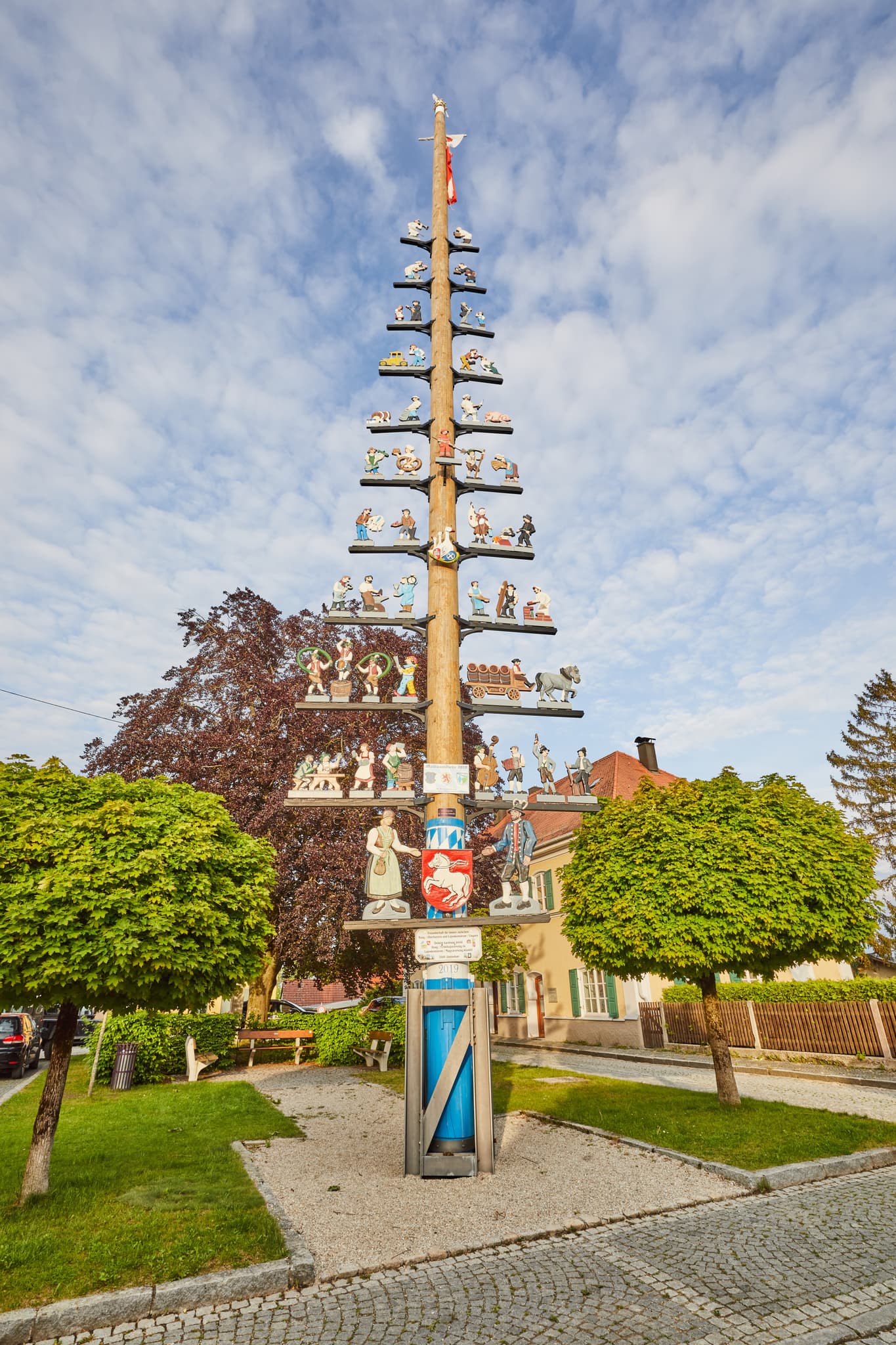 Bunter Maibaum in Haag, Mühldorf am Inn, Oberbayern - Ein festlich geschmückter Maibaum in Haag, Landkreis Mühldorf am Inn, Oberbayern, Region Inn-Salzach, Deutschland. Bei blauem Himmel und grünen Bäumen.