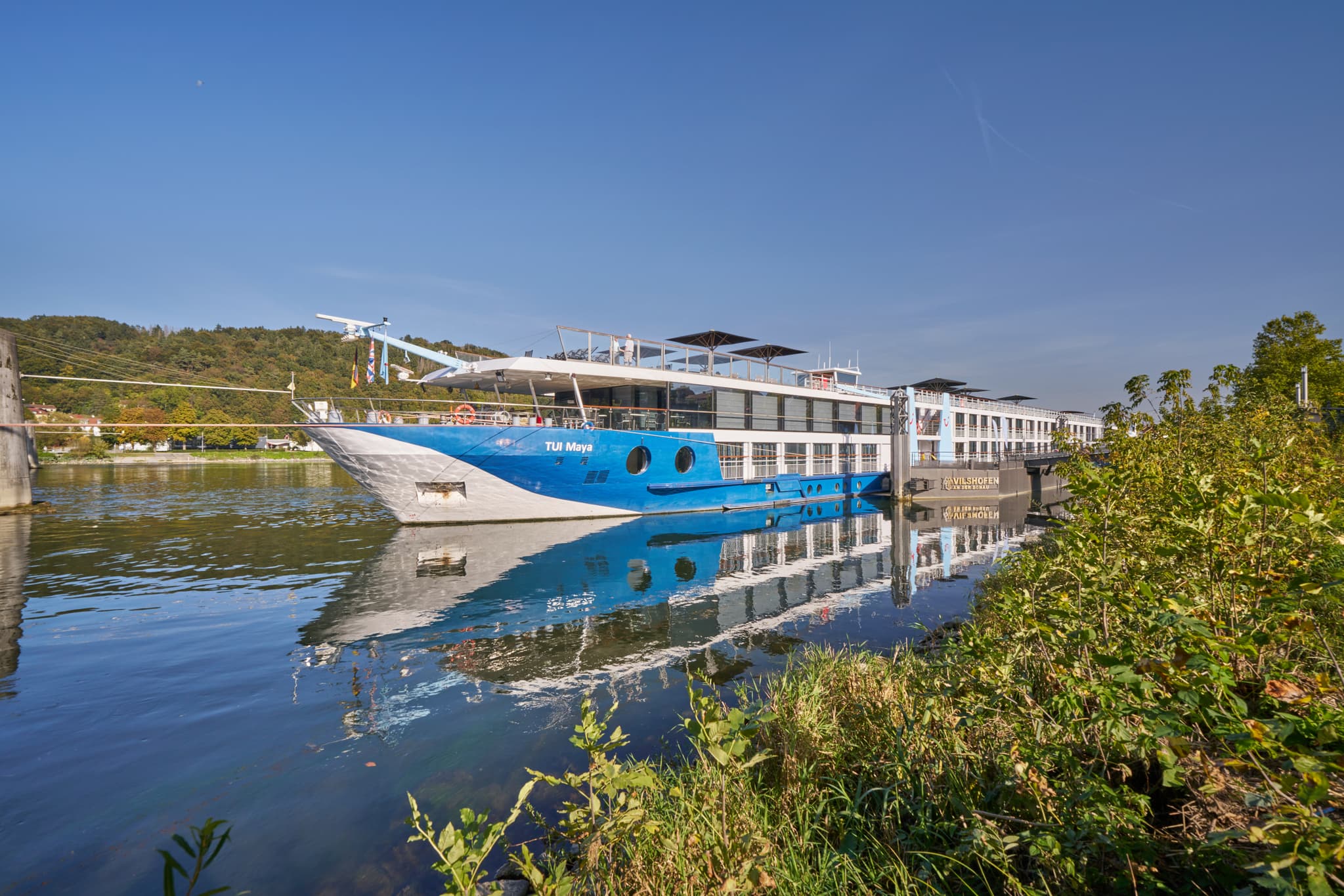 Donau Hafen Vilshofen, Landkreis Passau, Niederbayern - Flusskreuzfahrtschiff am Donau Hafen in Vilshofen, Landkreis Passau, Niederbayern, Deutschland. Zeigt das Schiff und die Donau-Wald-Landschaft bei Sonnenschein.