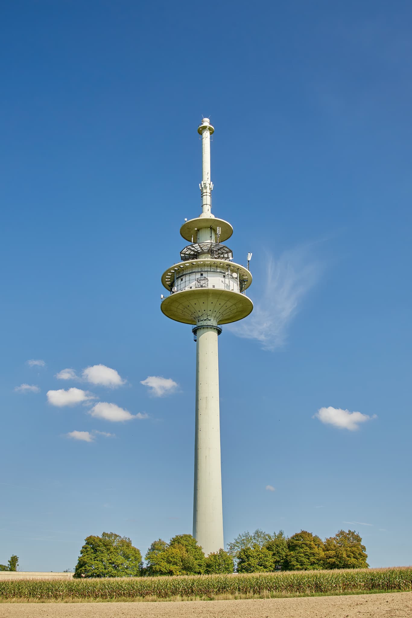 Funkanlage Schnaitsee, Landkreis Traunstein, Oberbayern - Funkanlage in Schnaitsee, Landkreis Traunstein, Oberbayern, Chiemgau, Deutschland. Hoch aufragender Telekommunikationsturm unter blauem Himmel über weitem Feld.
