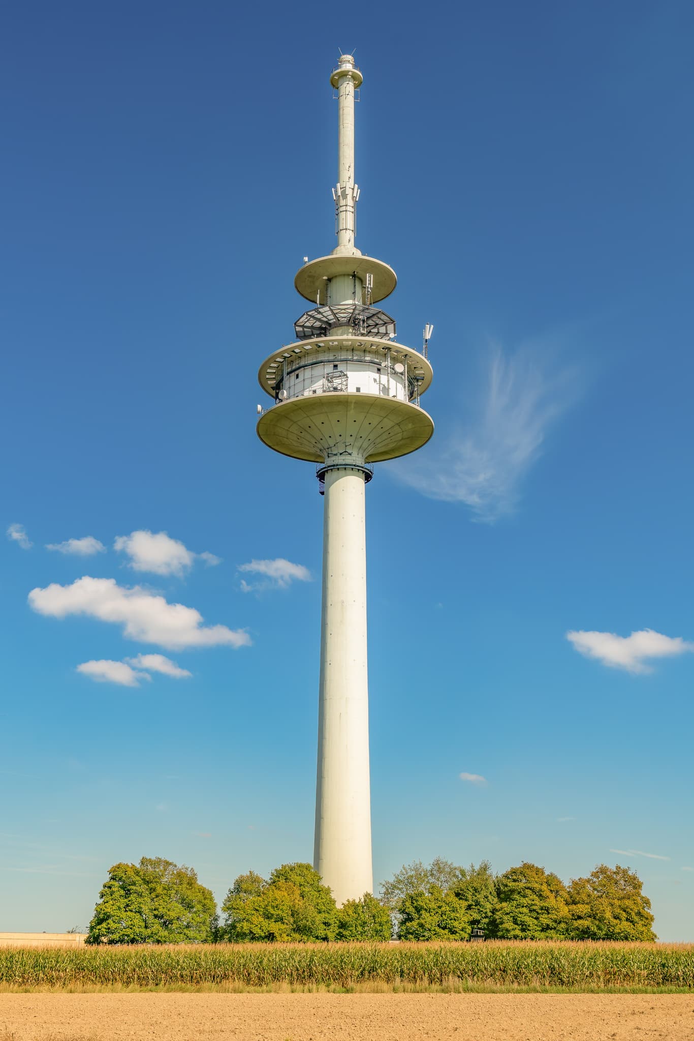 Funkturm Fernsehturm hoch, Schnaitsee, Traunstein - Funkturm, Fernsehturm in Schnaitsee, Landkreis Traunstein, Oberbayern, Deutschland. Das Bauwerk prägt die Region Chiemgau mit Feldern und blauem Himmel.