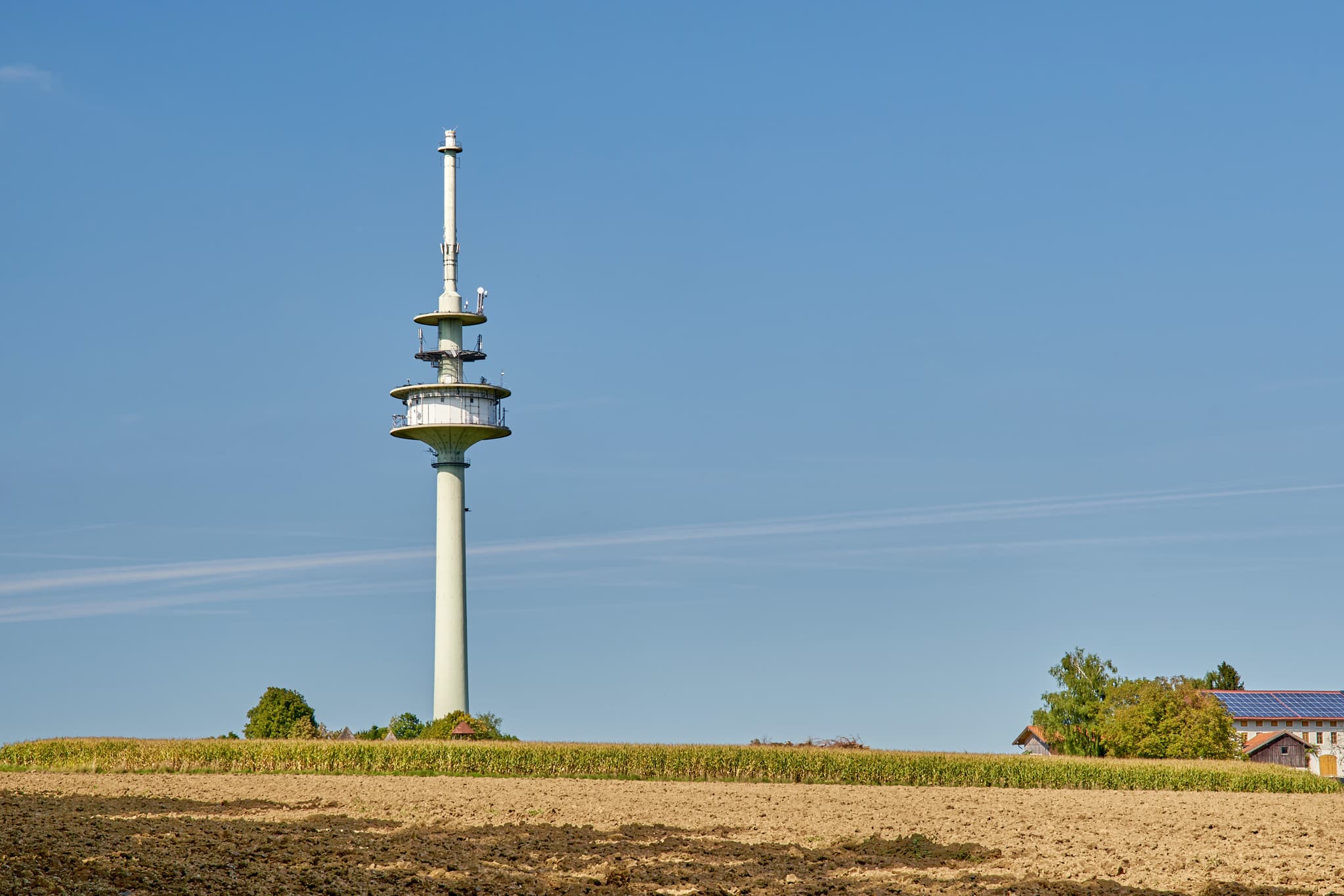 Funkturm in Schnaitsee, Landkreis Traunstein, Oberbayern - Funkturm bei Schnaitsee, Landkreis Traunstein, Oberbayern. Die ländliche Chiemgauer Landschaft in Deutschland mit Ackerland unter blauem Himmel ist zu sehen.