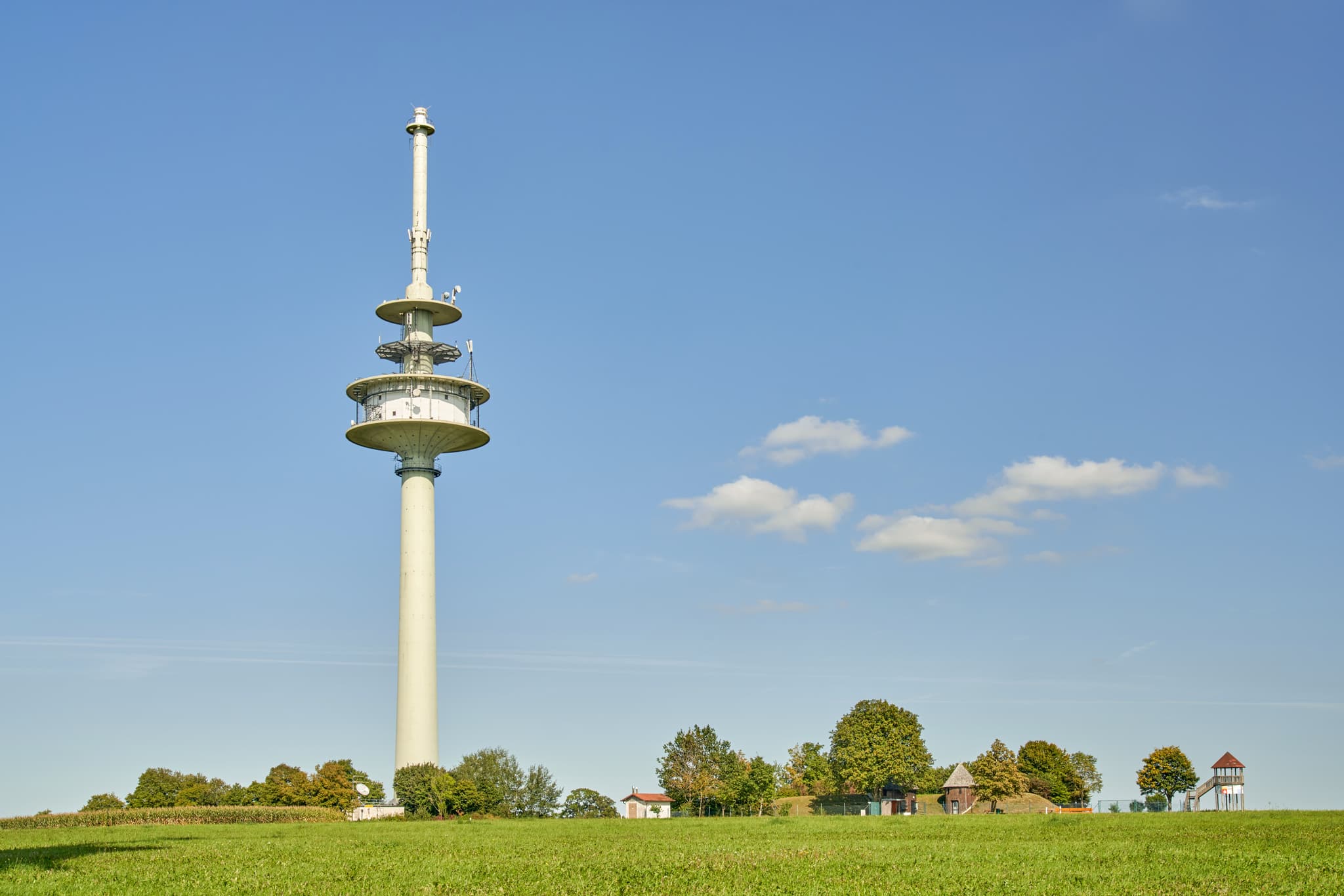 Funkturm Schnaitsee im Landkreis Traunstein, Oberbayern - Funkturm in ländlicher Landschaft bei Schnaitsee, Landkreis Traunstein, Oberbayern, Deutschland, zeigt weite Grünflächen unter blauem Himmel.