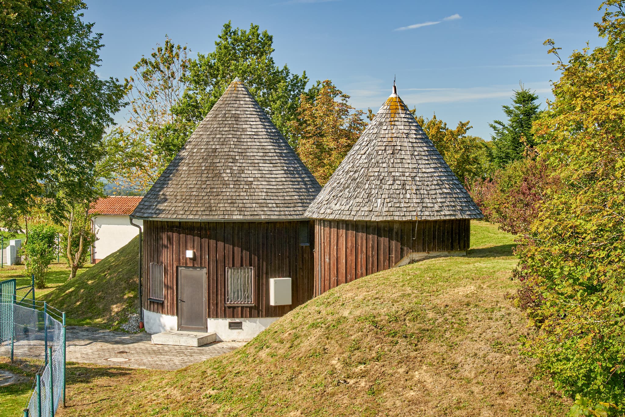 Häuschen auf dem Funkturmgelände, Schnaitsee, Traunstein - Zwei Holzhäuschen mit Spitzdächern auf Funkturmgelände Schnaitsee, Traunstein, Oberbayern, Chiemgau, Deutschland. Ungewöhnliche Gebäude in grüner Landschaft.