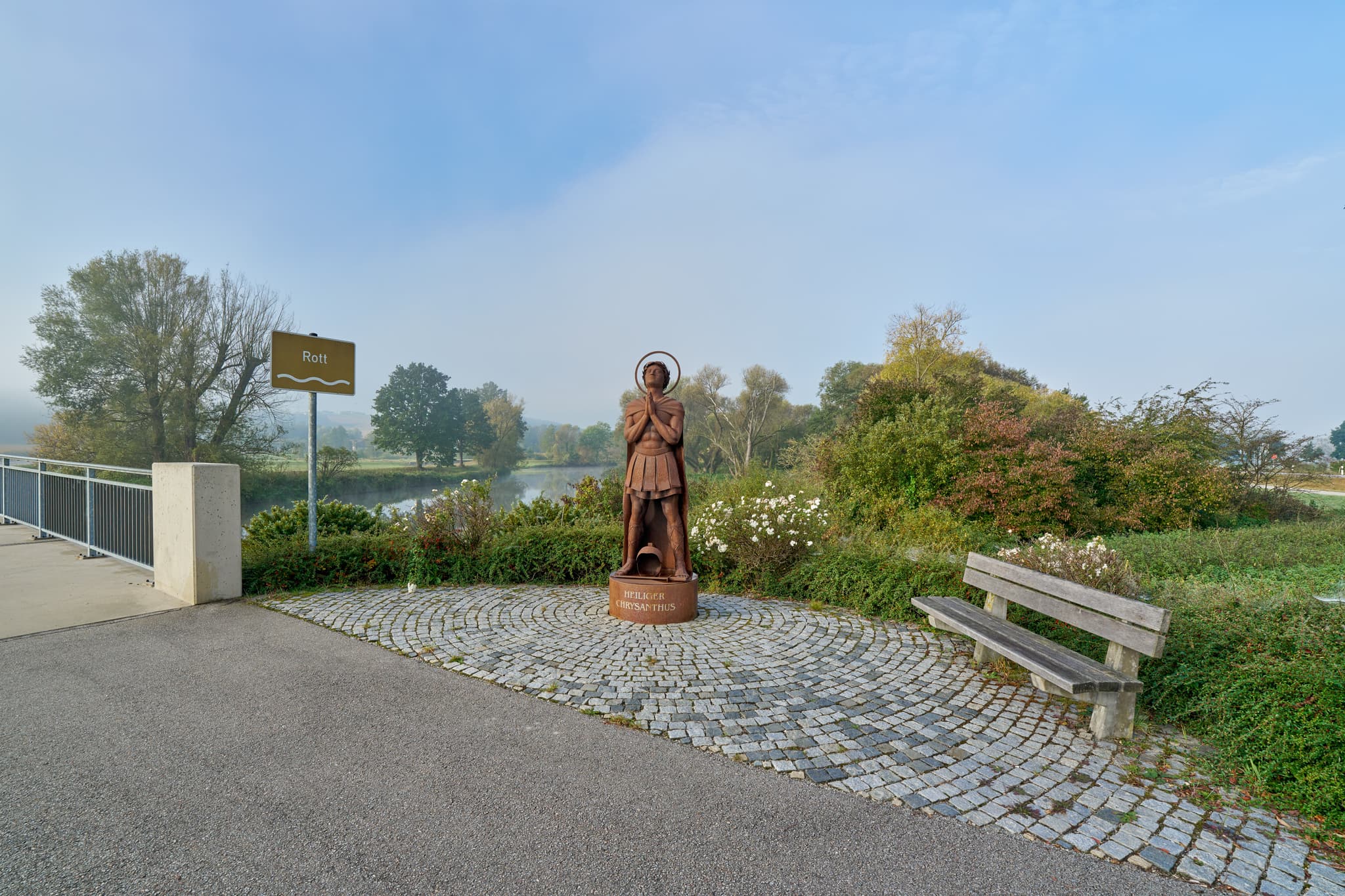 Heiliger Chrysanthus, Rott, Bad Birnbach, Bäderdreieck - Die herbstliche Rottlandschaft in Bad Birnbach, Landkreis Rottal-Inn, Niederbayern, Region Bäderdreieck, Deutschland. Eine Statue mit Brücke und Fluss im Nebel.