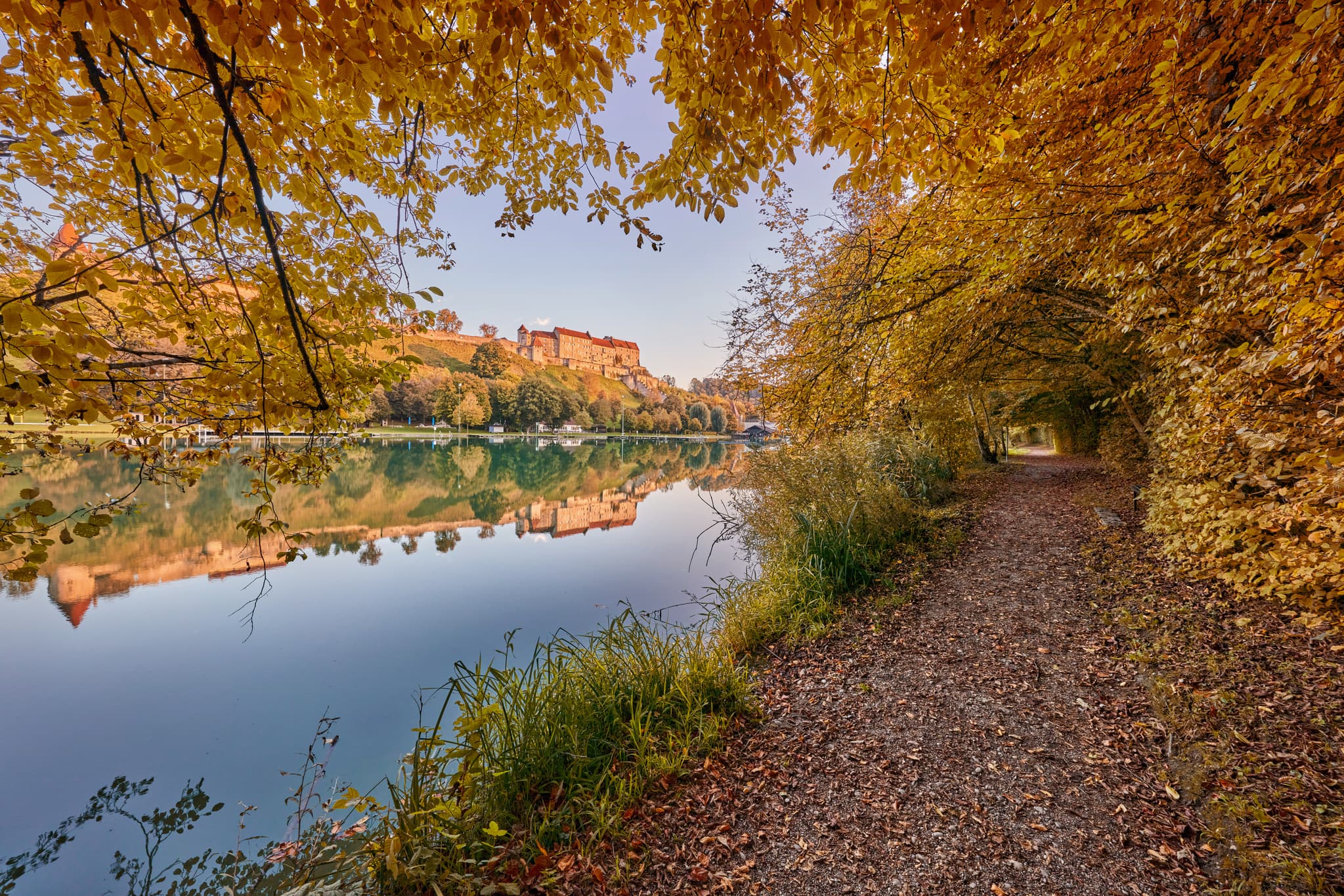 Herbst am Wörthsee mit Burghausen, Oberbayern, Inn-Salzach - Herbstliche Landschaft am Wöhrsee in Burghausen, Altötting, Oberbayern. See mit Laubengang und Burgsilhouette im Hintergrund, gelegen in der Inn-Salzach Region.
