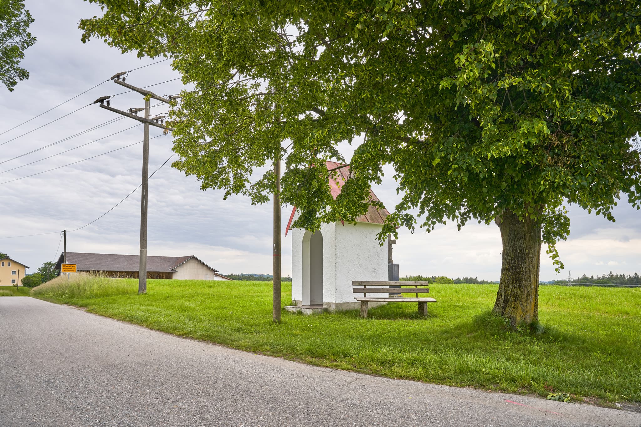 Höresham Bildstock mit Grabstein, Oberbayern, Inn-Salzach - Bildstock mit Grabstein und Bank in Höresham, Burgkirchen, Altötting. Ländliche Szenerie in Oberbayern, Inn-Salzach. Baum, Wiesen, Bauernhof.