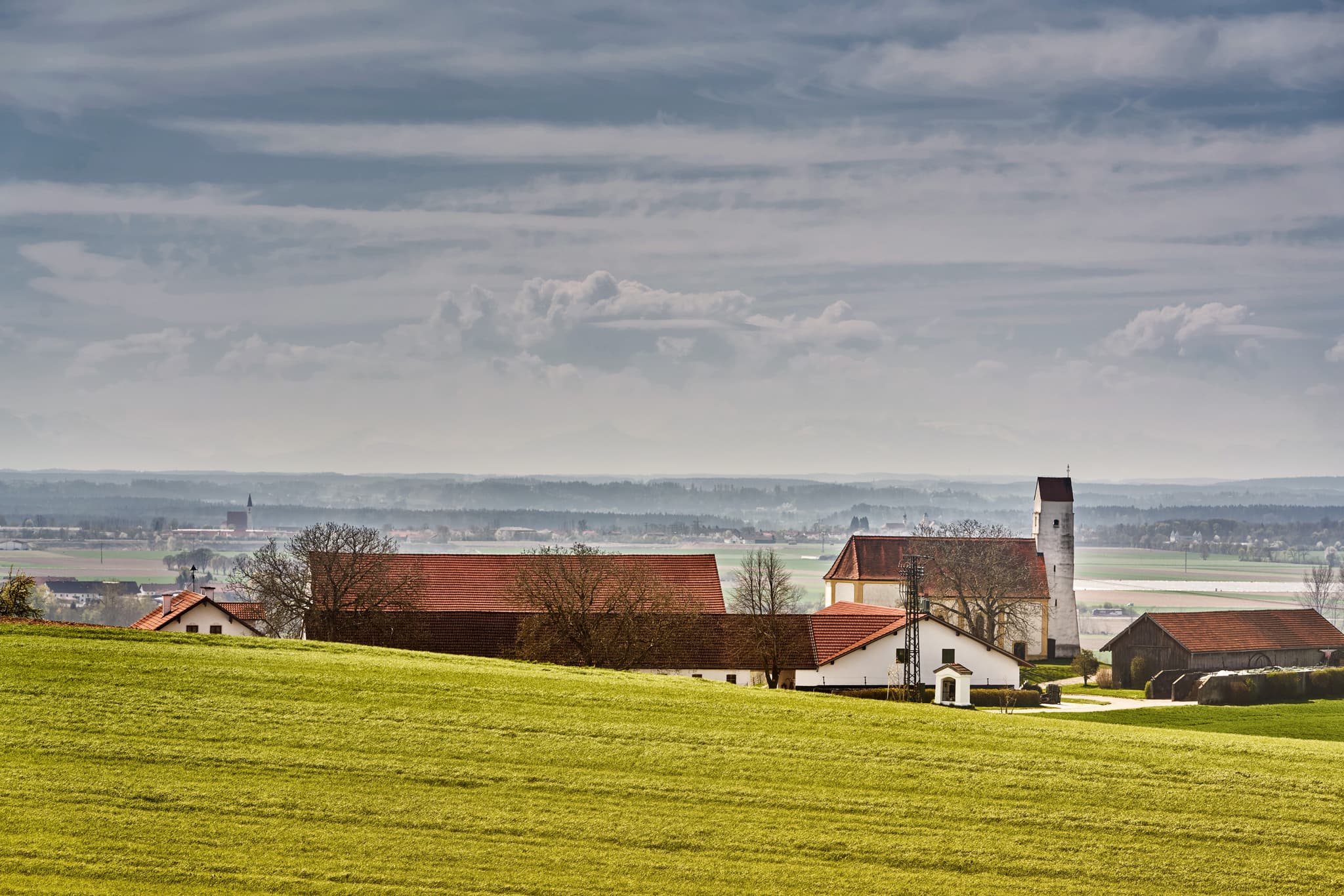 Kirchisen Mettenheim, Mühldorf am Inn, Oberbayern - Idyllische Landschaft in Mettenheim, Mühldorf am Inn, Oberbayern. Kapelle mit Bäumen am Feldweg, umgeben von Feldern u. Höfen.