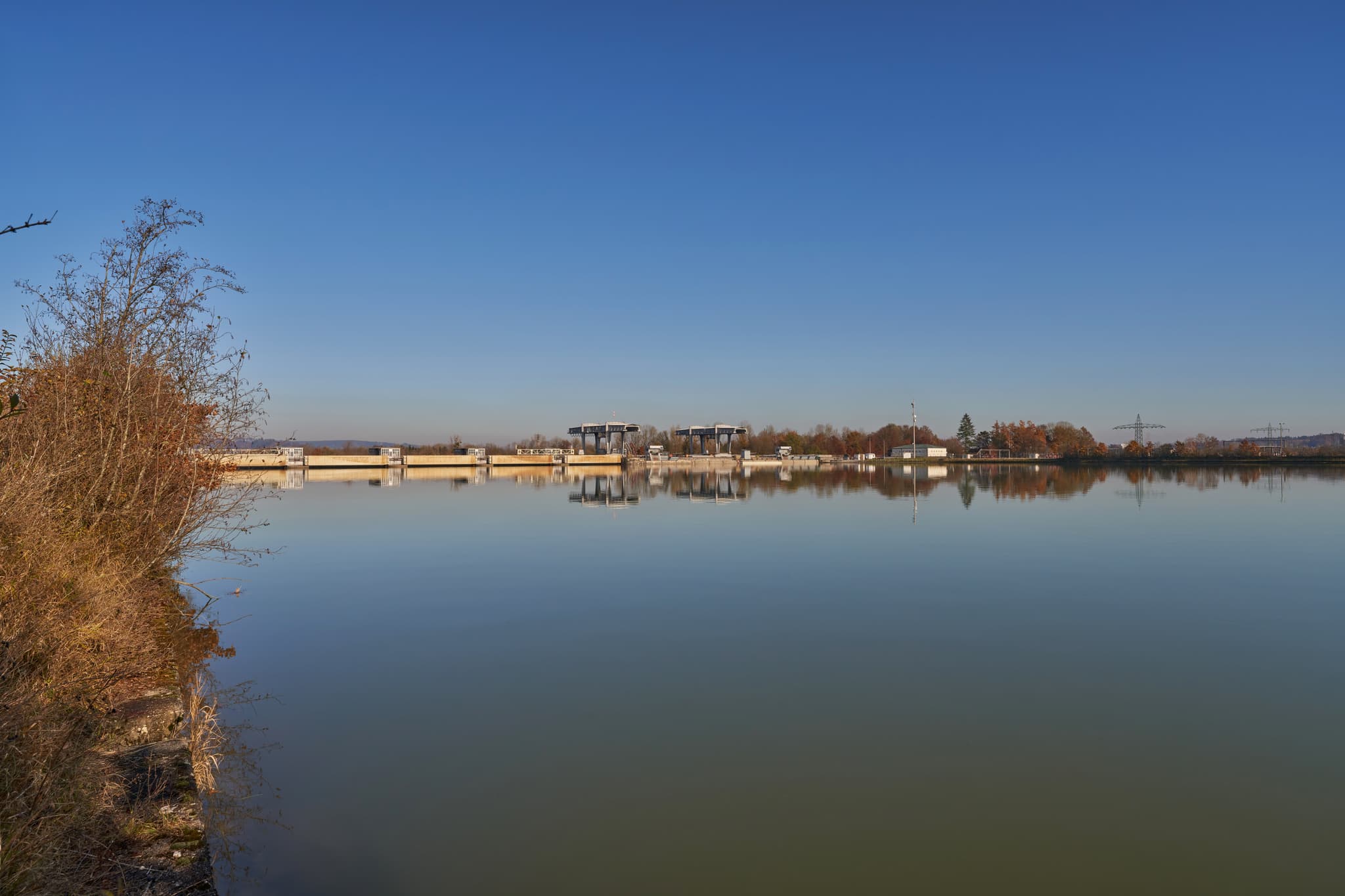 Kraftwerk Simbach-Braunau, PAN, Niederbayern, Bäderdreieck - Blick auf Kraftwerk Simbach-Braunau bei Kirchdorf am Inn, Rottal-Inn, Niederbayern. Die Anlage am Inn spiegelt sich im ruhigen Gewässer wider.