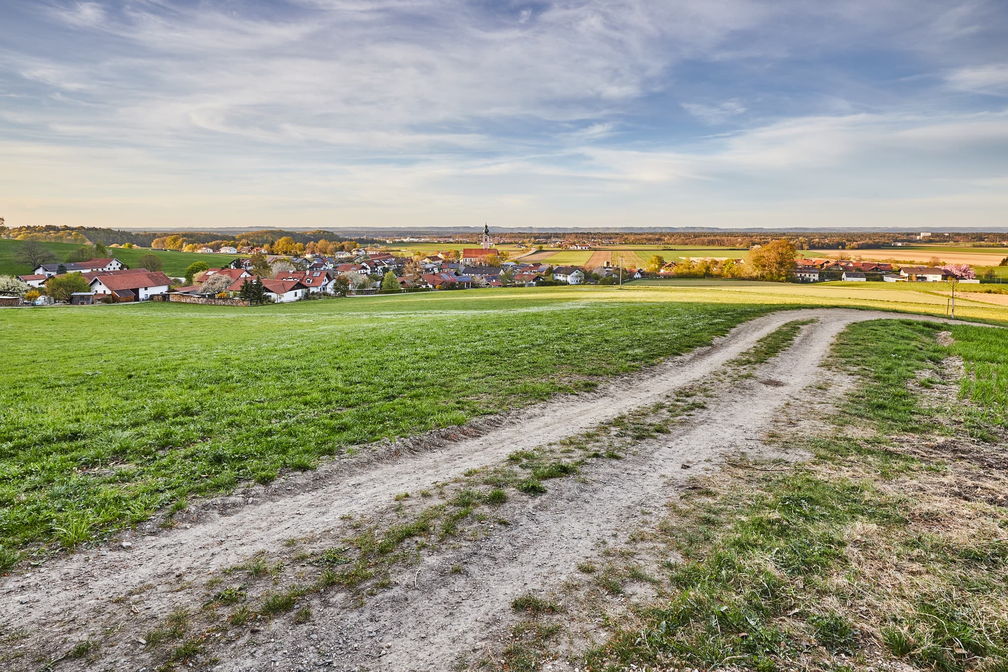 Landschaft mit Weg, Hörndlweg, Altötting, Oberbayern - Ländliche Ansicht mit Feldweg durch grüne Wiesen. Im Hintergrund Dorf Mehring (Hörndlweg), Landkreis Altötting, Oberbayern. Teil der Region Inn-Salzach.