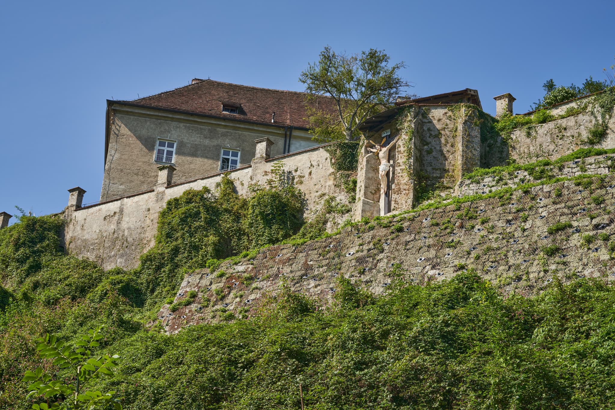 Marienweg, Benediktweg, Raitenhaslach, Burghausen, Altötting - Kloster Raitenhaslach in Burghausen, Altötting, Landkreis Altötting, Oberbayern, Inn-Salzach, Bayern, Deutschland. Die Bebauung ist von dichtem Grün bedeckt.