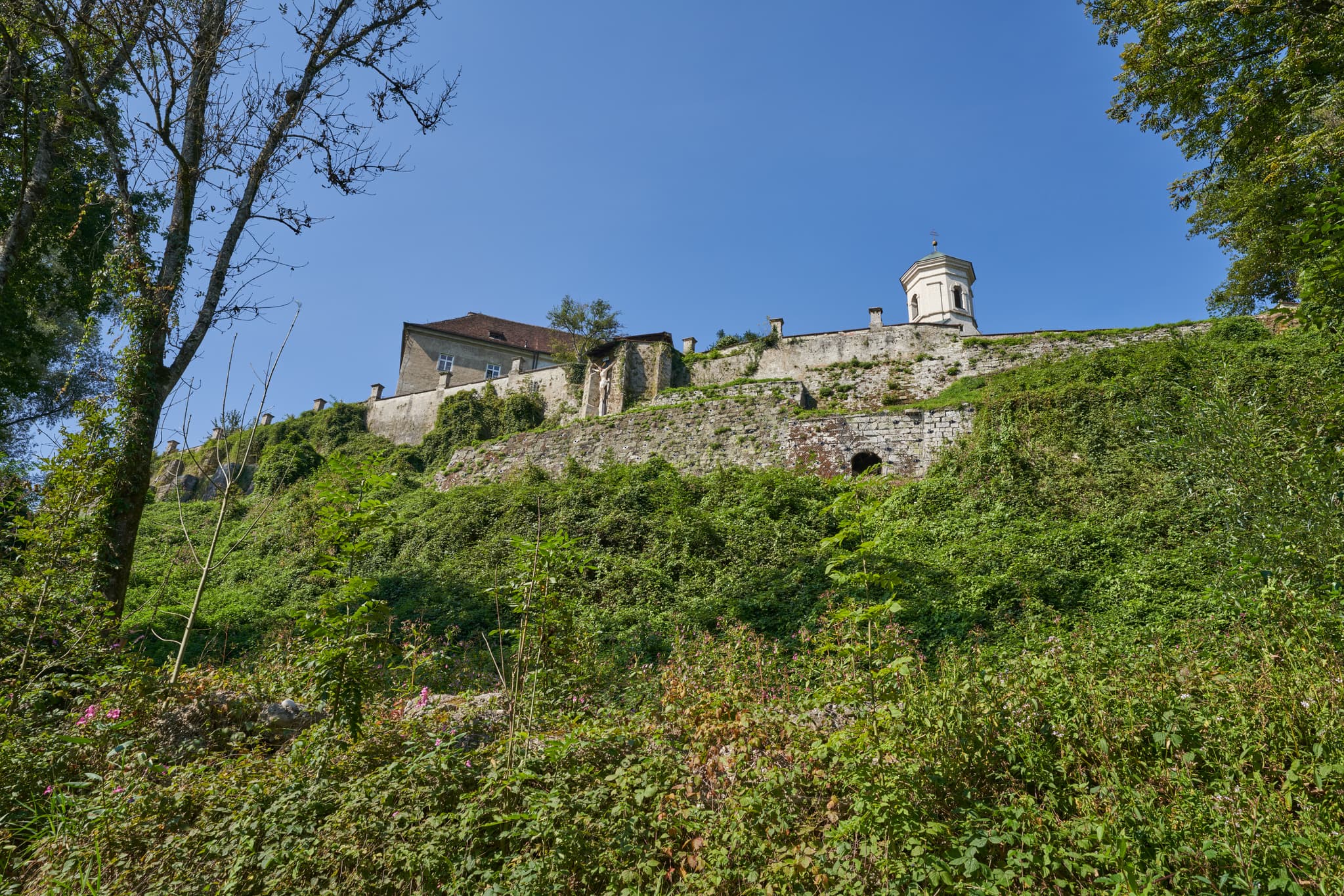 Marienweg, Benediktweg, Raitenhaslach, Burghausen, Altötting - Kloster Raitenhaslach in Burghausen, Altötting, Landkreis Altötting, Oberbayern, Inn-Salzach, Bayern, Deutschland. Die Bebauung ist von dichtem Grün bedeckt.