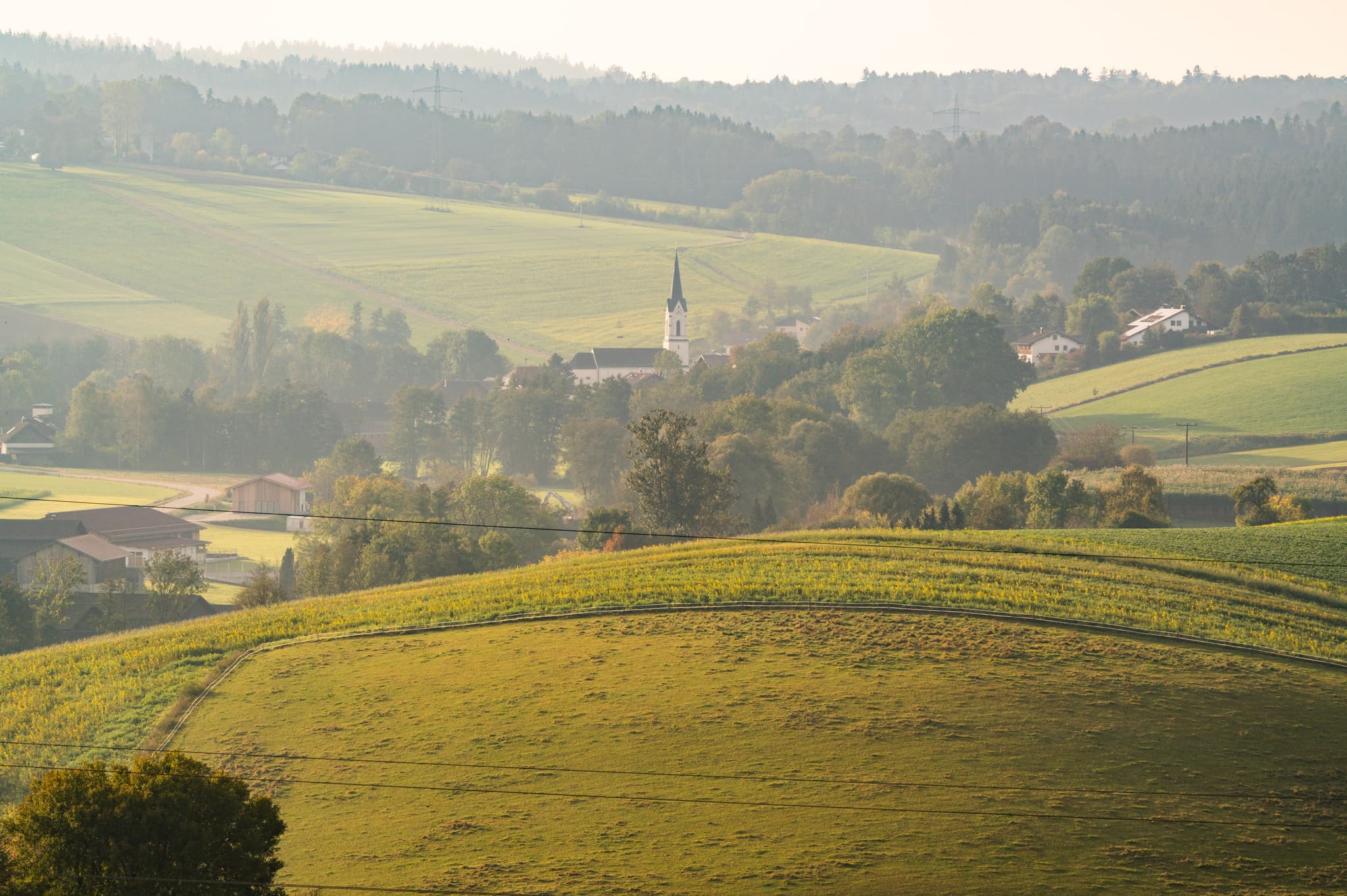 Neudeck Aussicht Asenham, PAN, Niederbayern, Bäderdreieck - Blick auf sanfte Hügel, weite Felder und ein Dorf mit Kirchturm bei Neudeck Aussicht Asenham, Bad Birnbach, Rottal-Inn, Niederbayern, Bäderdreieck, Deutschland.