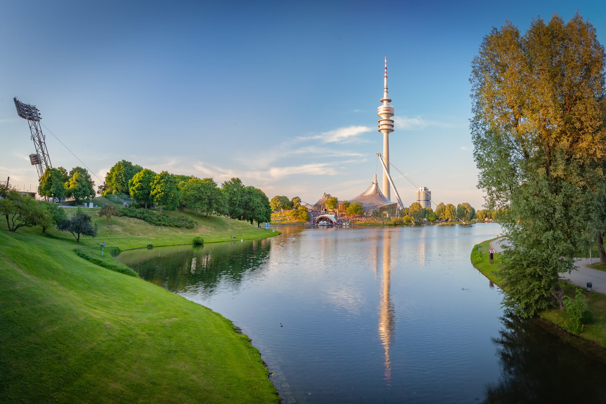 Olympiapark mit Olympiaturm und See, München, Oberbayern - Panoramablick auf Olympiapark 2 mit Olympiasee und Olympiaturm in München, Deutschland. Grüne Ufer, Landkreis München, Oberbayern, Zentralraum München.