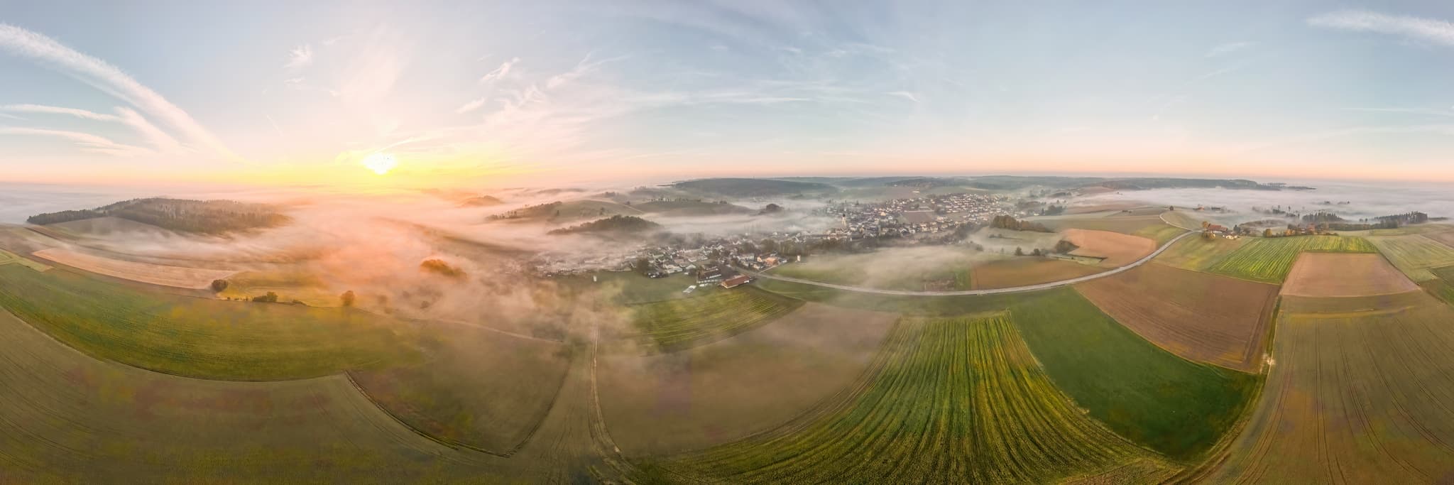 Ortsansicht Markt Landschaft Kößlarn, Passau, Niederbayern - Blick auf Kößlarn, Markt im Landkreis Passau, Niederbayern, Deutschland. Landschaft im Donau-Wald mit Feldern und Hügeln, eingehüllt in Nebel zum Sonnenaufgang.