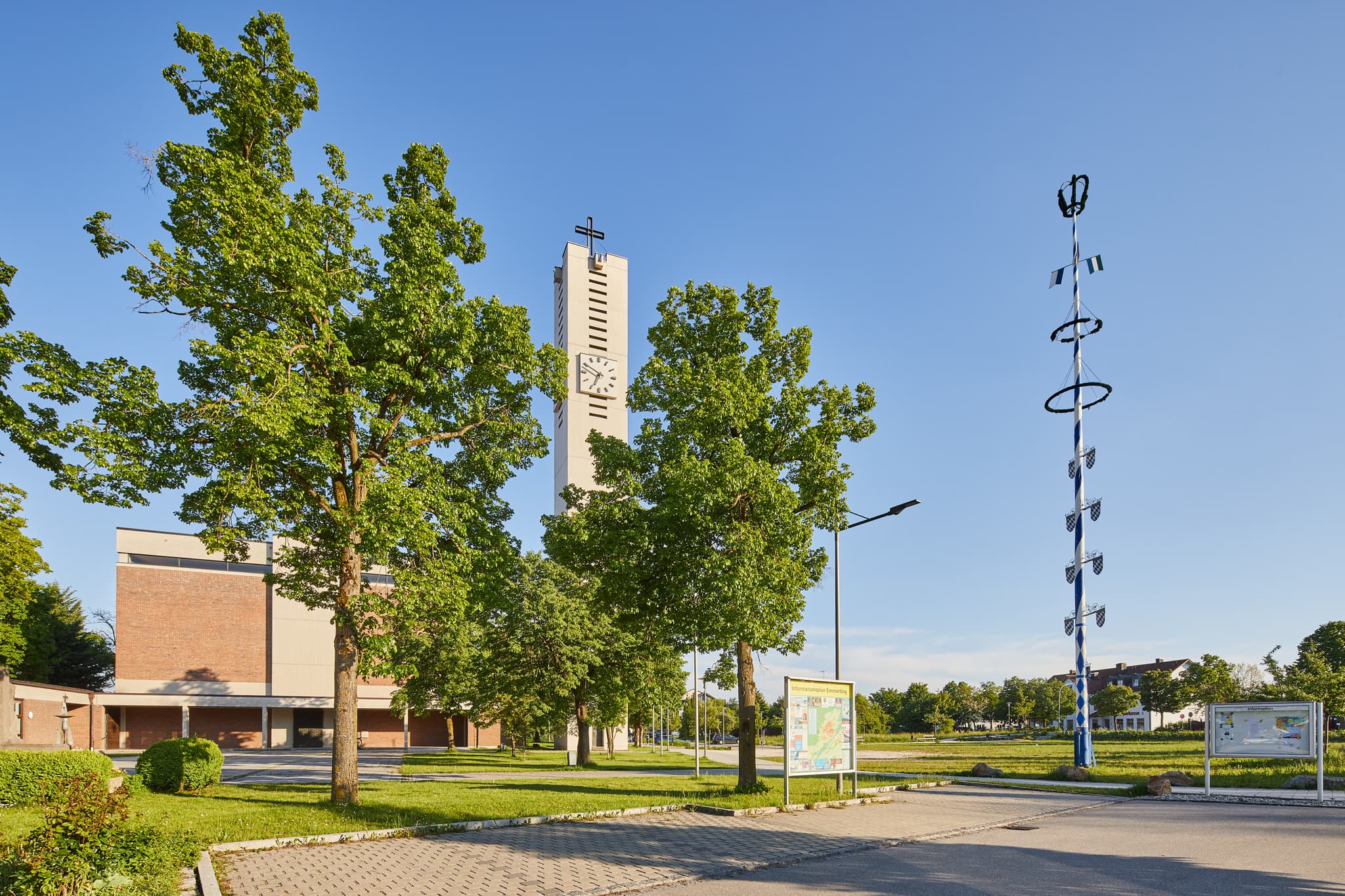 Pfarrkirche Heilig Geist, Emmerting, Altötting, Oberbayern - Die Pfarrkirche Heilig Geist in Emmerting, Altötting, Oberbayern, Inn-Salzach, Deutschland, zeigt ihren Kirchturm und  Maibaum unter blauem Himmel.