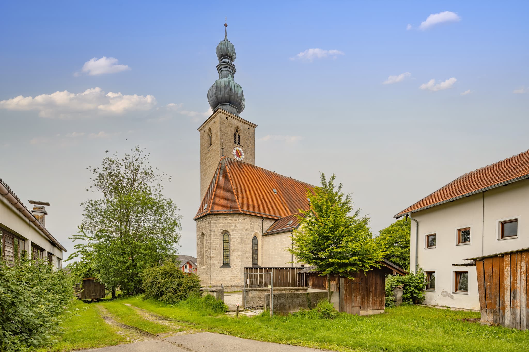 Pfarrkirche St. Johann Baptist, Tyrlaching, Altötting - Die Pfarrkirche St. Johann Baptist in Tyrlaching, Landkreis Altötting, Oberbayern, Inn-Salzach, Deutschland. Ländlich gelegen, umgeben von Grün und Gebäuden.