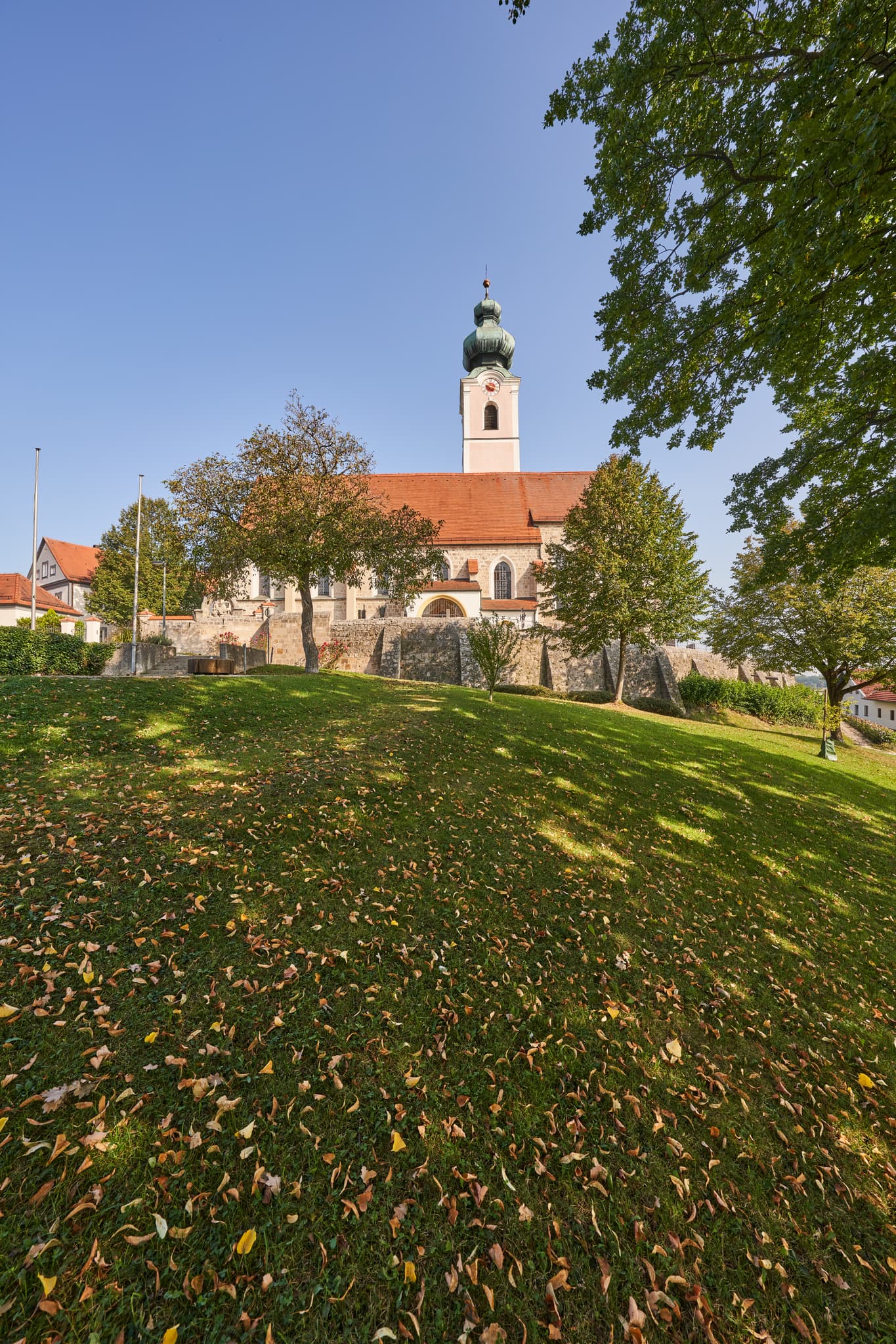 Pfarrkirche St. Michael, Mehring, Altötting, Oberbayern - Pfarrkirche St. Michael in Mehring, Altötting, Oberbayern, Inn-Salzach, Deutschland. Herbstlaub im Vordergrund unter blauem Himmel.