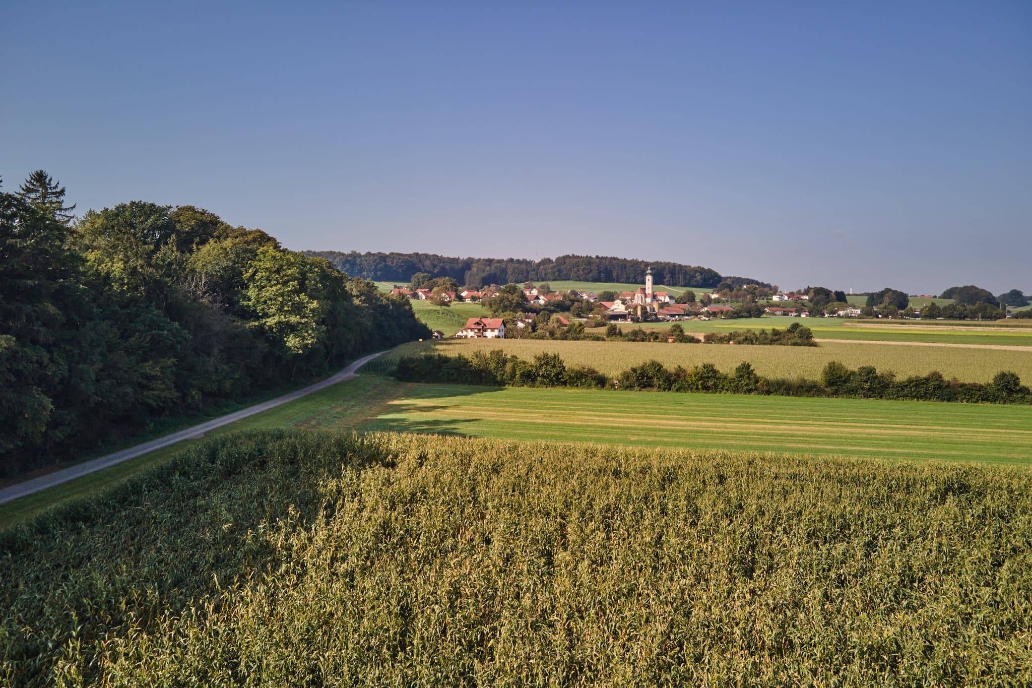 Pilgerweg Richtung Mehring, Badhöring, Altötting, Oberbayern - Pilgerweg Richtung Mehring bei Badhöring, Altötting, Oberbayern, Deutschland. Ländliche Szenerie mit Feldern, Straße und Dorf im Inn-Salzach-Gebiet.