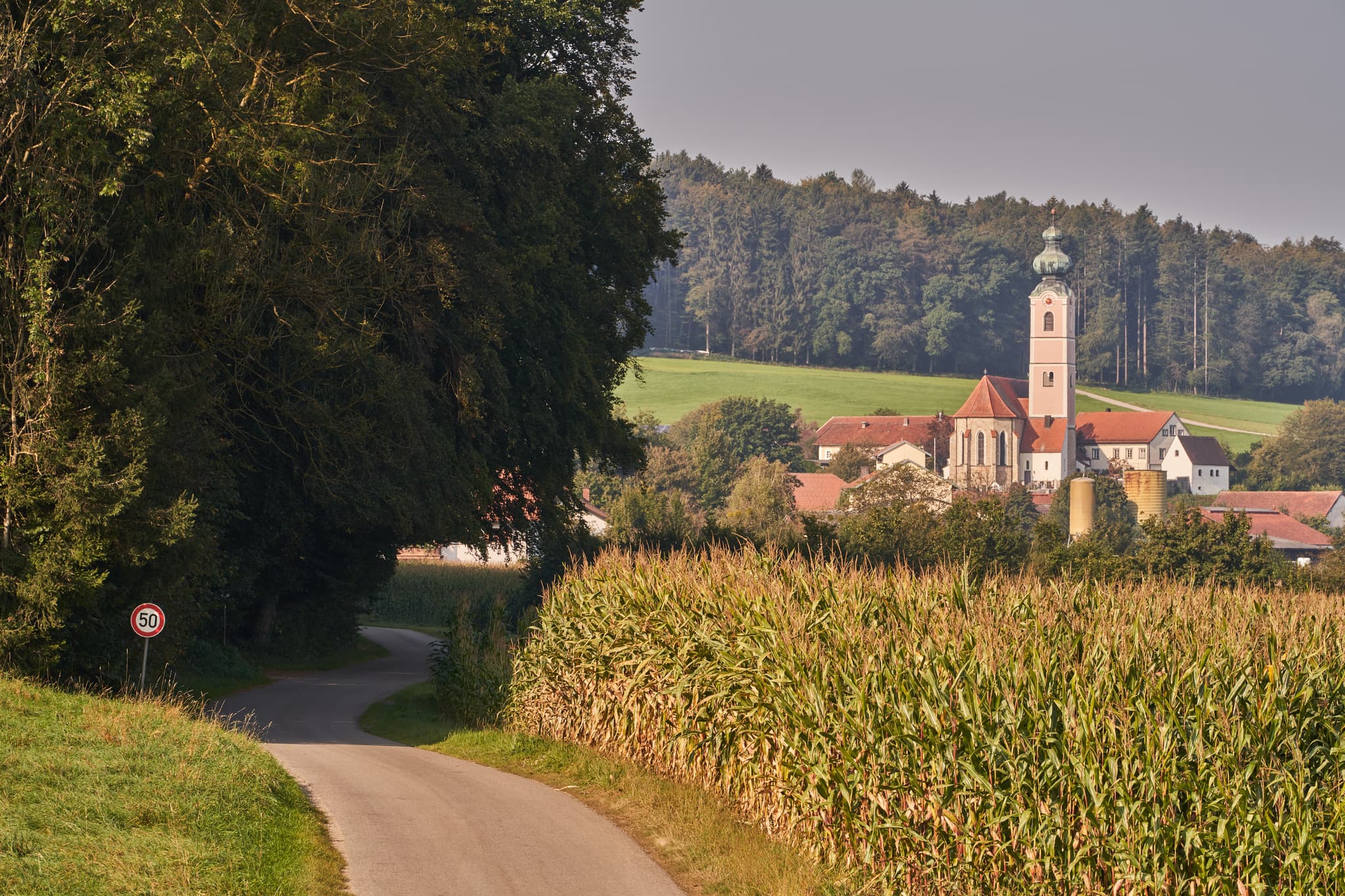 Pilgerweg Richtung Mehring, Badhöring, Altötting, Oberbayern - Pilgerweg durch Felder bei Badhöring, einem Ortsteil von Mehring. Blick auf das Dorf mit Kirche in Altötting, Oberbayern, Region Inn-Salzach, Deutschland.