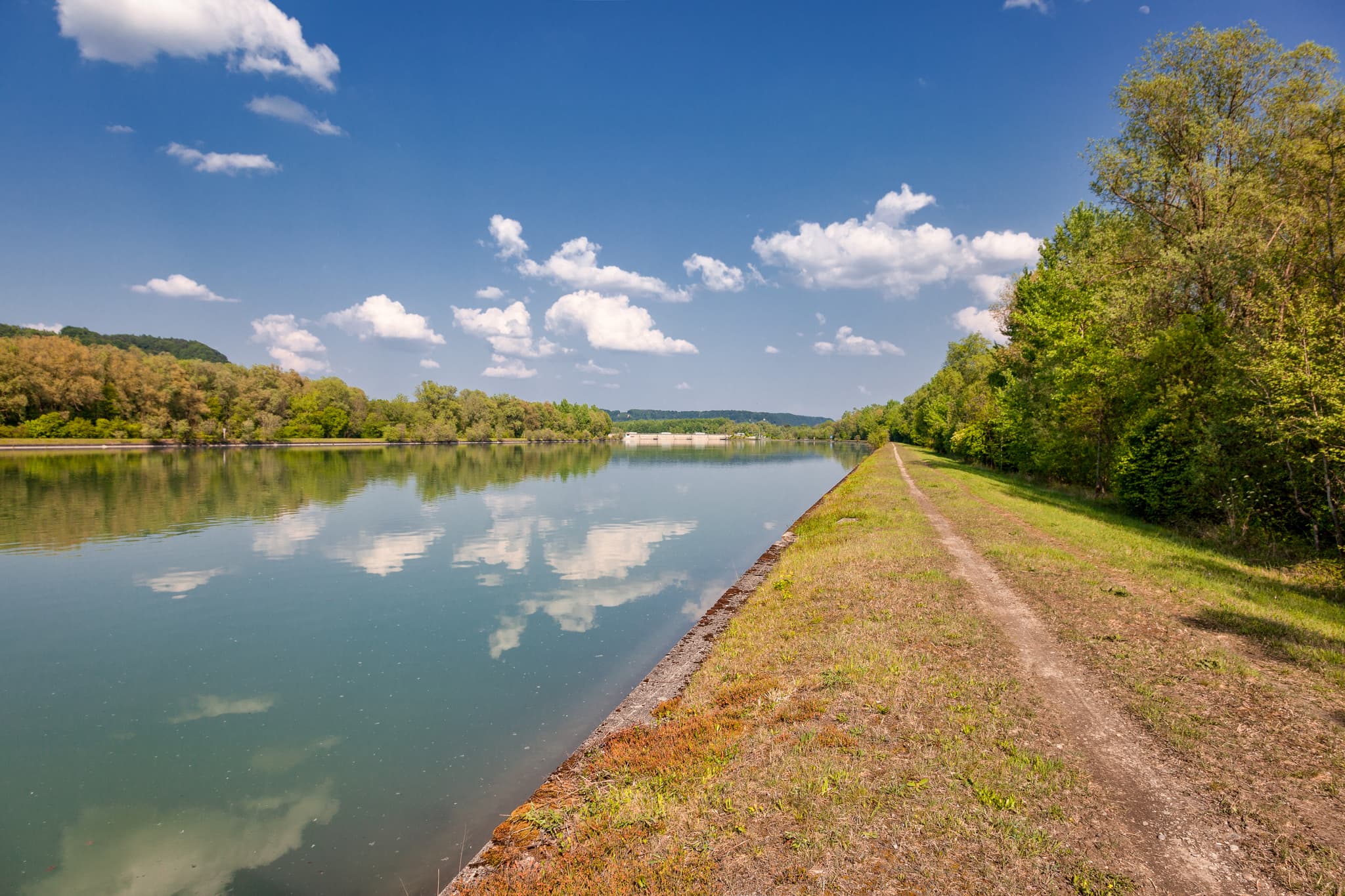 Radweg rechte Seite, Inn Kraftwerk Perach, Altötting - Der Radweg am Inn Kraftwerk Perach bei Neuötting im Landkreis Altötting, Oberbayern, Deutschland. Zeigt ruhige Flusslandschaft Inn-Salzach mit grünen Ufern.