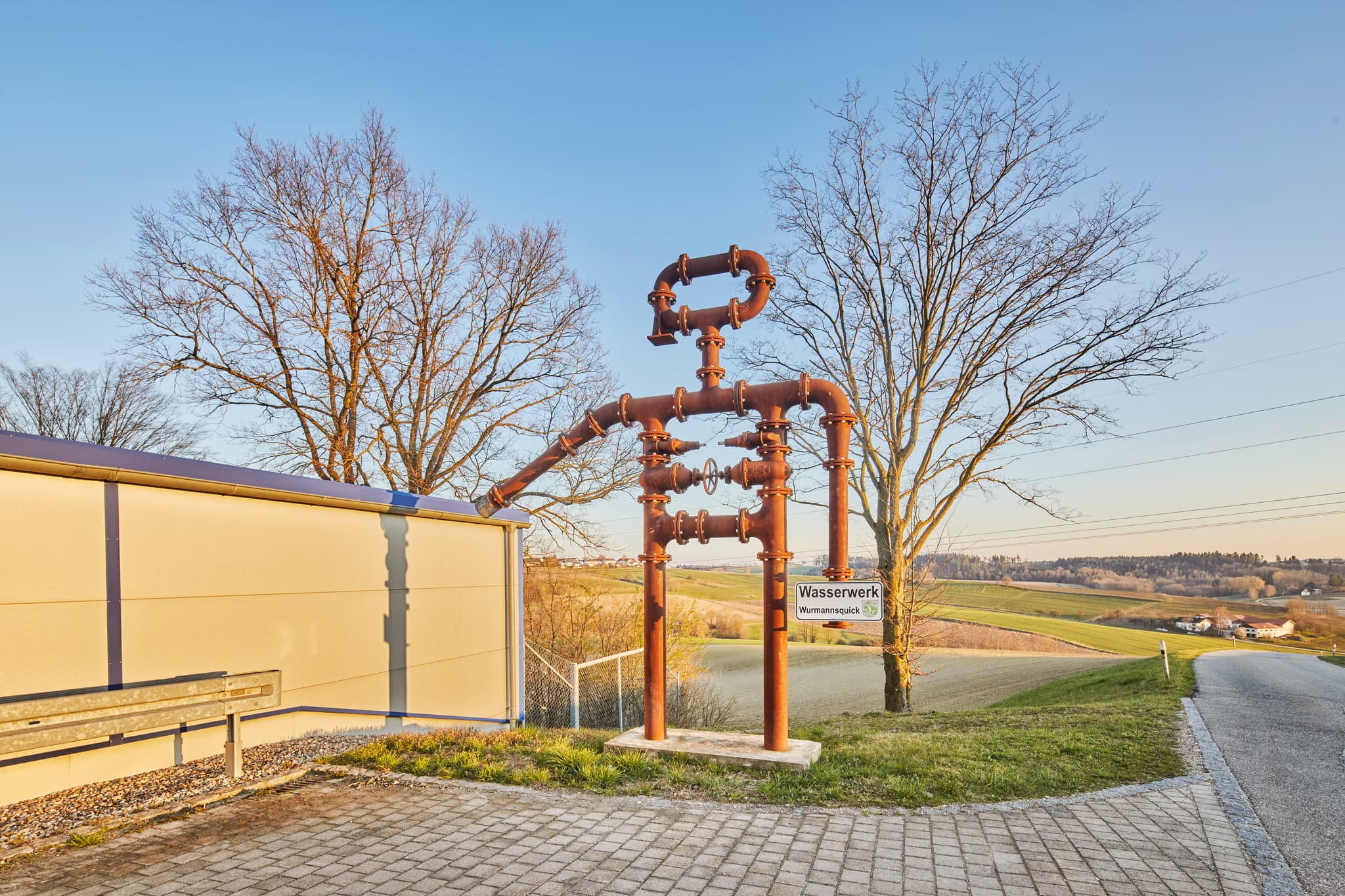 Rohrmännchen am Wasserwerk Wurmannsquick, Rottal-Inn - Wasserwerk in Wurmannsquick, Gemeinde Wurmannsquick, Landkreis Rottal-Inn, Niederbayern, Holzland, Bayern, Deutschland. Bild zeigt eine Installation aus Rohren.