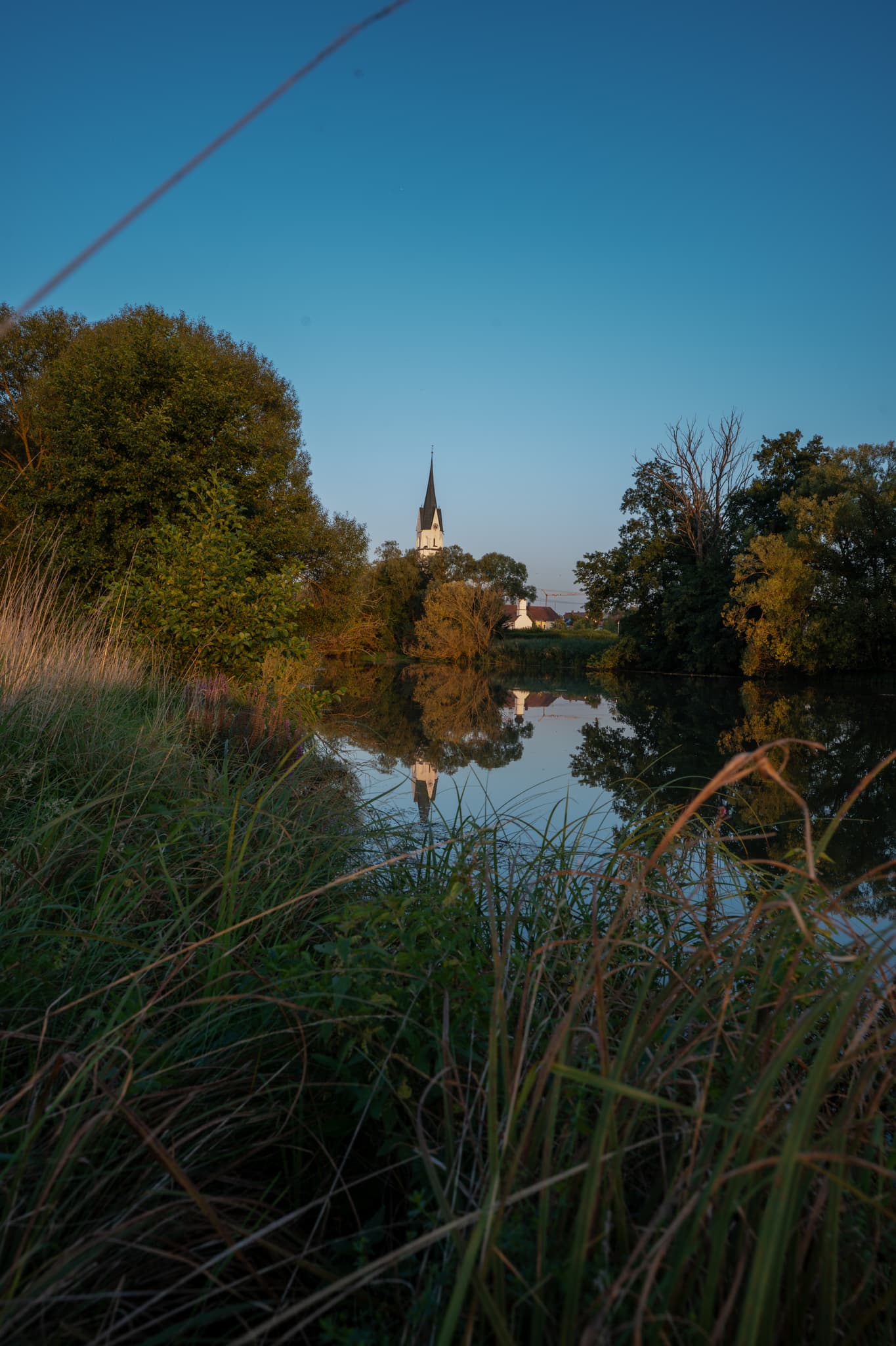 Rott in Unterdietfurt mit Blick zu kirchel - Friedliche Abendstimmung in Unterdietfurt. Der Kirchturm spiegelt sich in ruhigen Wasser,Warme Farben und weiches Licht erzeugen eine beschauliche Atmosphäre