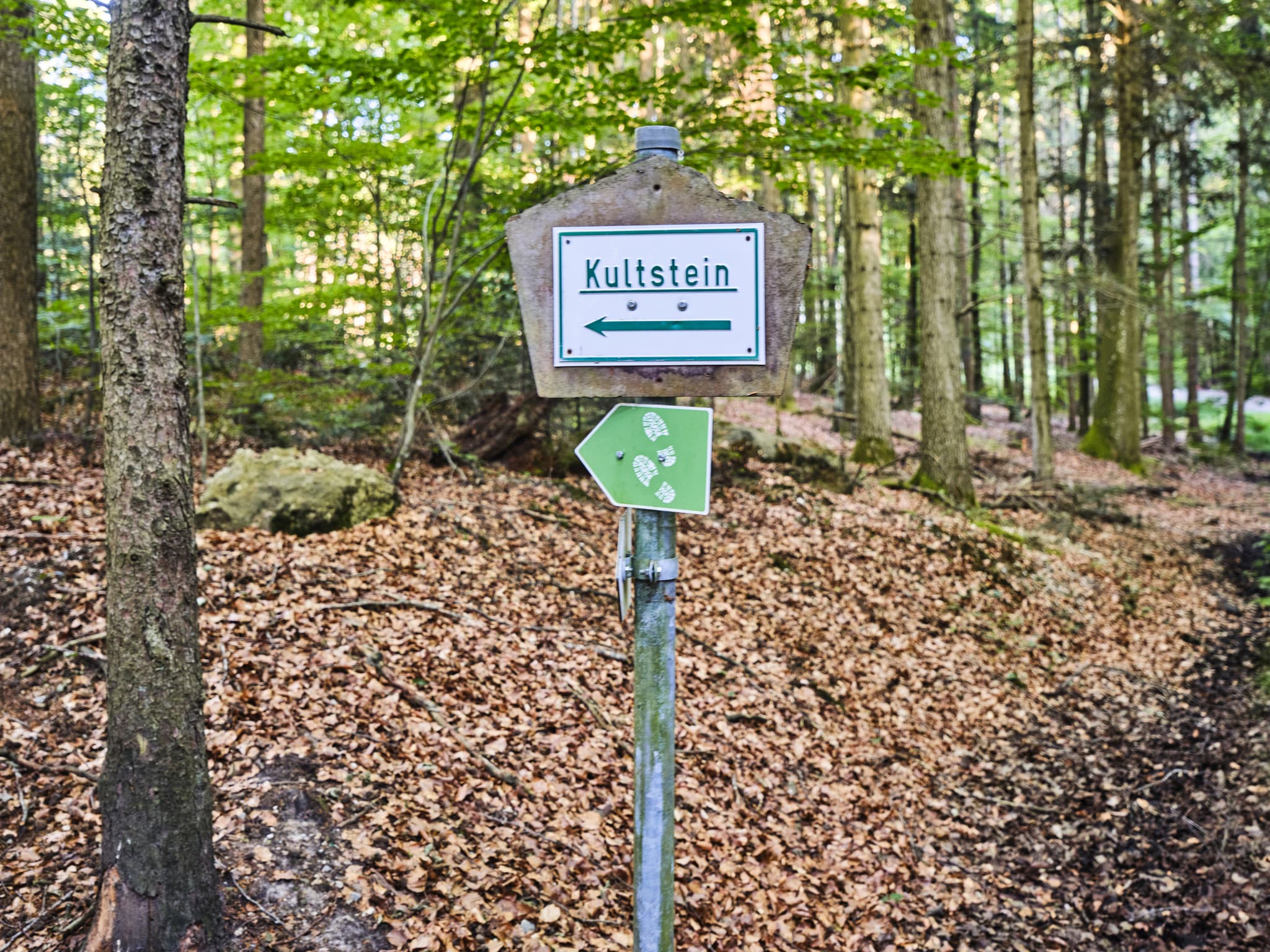 Schild zum Kultstein, St. Salvator, Bad Griesbach, Passau - Wegweiser Kultstein bei St. Salvator, Bad Griesbach, Landkreis Passau, Niederbayern, Deutschland. Bild zeigt einen Waldweg mit Blätterboden.