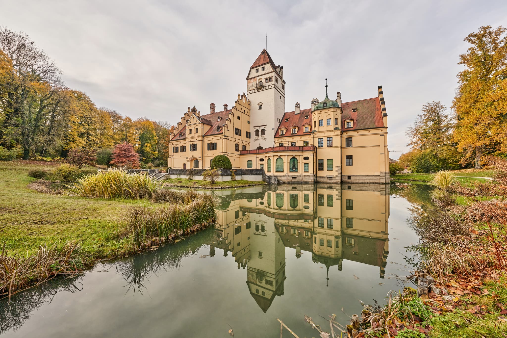 Schlosspark mit Wassergraben Hörniweg, Schönau, Rottal-Inn - Schloss Schönau, Rottal-Inn, Niederbayern. Bauwerk mit Schlosspark und Wassergraben, spiegelt sich im Wasser. Herbstliche Natur im Holzland, Deutschland.