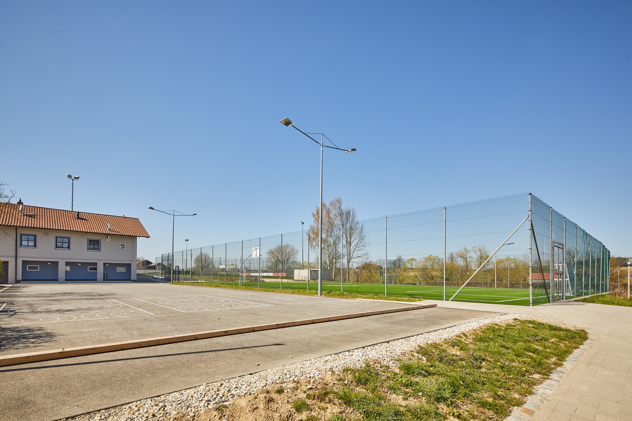 Sportanlage in Unterdietfurt, Rottal-Inn, Niederbayern - Sportanlage Unterdietfurt, Rottal-Inn, Niederbayern. Blick auf Sportfeld, asphaltierten Platz, Gebäude. Gelegen im Holzland, Deutschland, unter blauem Himmel.