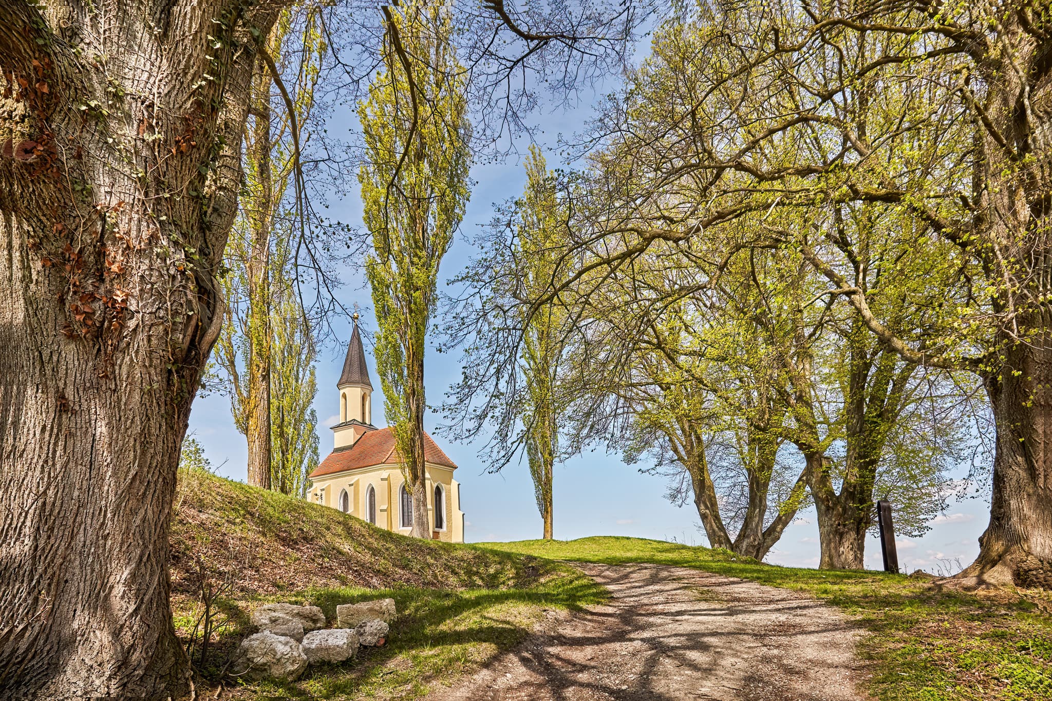 St.-Georgs-Kirchlein, Schlossberg, Mühldorf am Inn - St.-Georgs-Kirchlein auf dem Schlossberg in Kraiburg, Mühldorf am Inn, Oberbayern, Inn-Salzach, Deutschland. Kleine Kirche auf grünem Hügel, umrahmt von Bäumen.