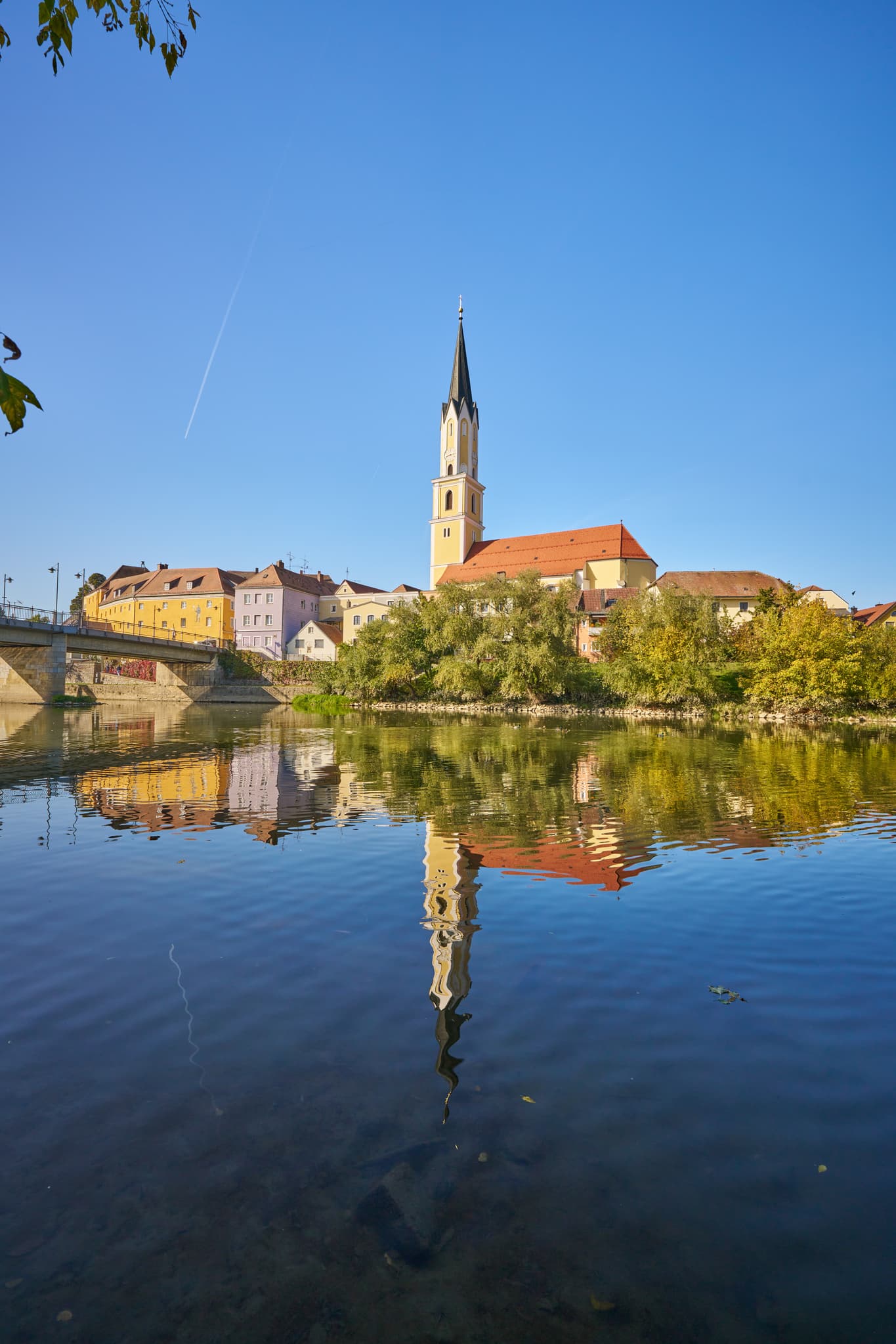 Stadtpfarrkirche St. Johannes der Täufer, Vilshofen / Vils - Stadtansicht von Vilshofen an der Vils im Landkreis Passau, Niederbayern. Stadt am Fluss mit Kirche, spiegelt sich im Wasser. Region Donau-Wald, Deutschland.