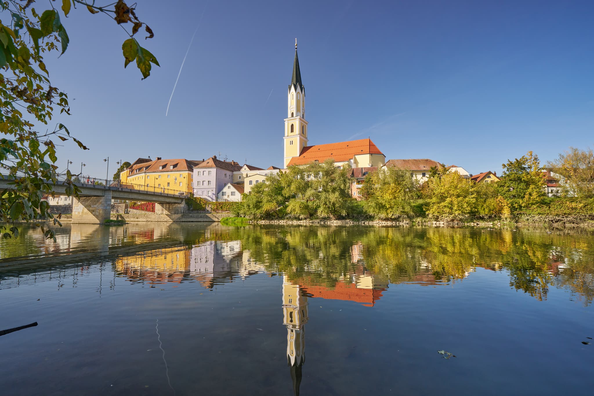 Stadtpfarrkirche St. Johannes der Täufer, Vilshofen / Vils - Stadtansicht von Vilshofen an der Vils im Landkreis Passau, Niederbayern. Stadt am Fluss mit Kirche, spiegelt sich im Wasser. Region Donau-Wald, Deutschland.