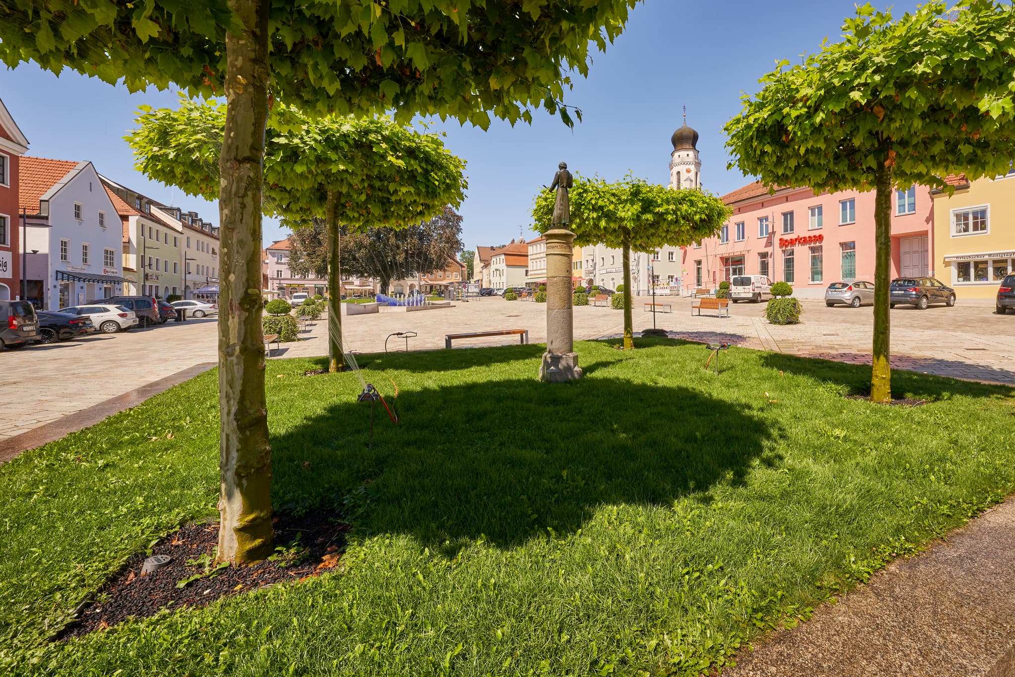 Stadtplatz Platanen, Bad Griesbach, Passau, Niederbayern - Blick auf den sonnigen Stadtplatz in Bad Griesbach im Landkreis Passau, Niederbayern, Deutschland. Platanen, Statue und historische Gebäude.
