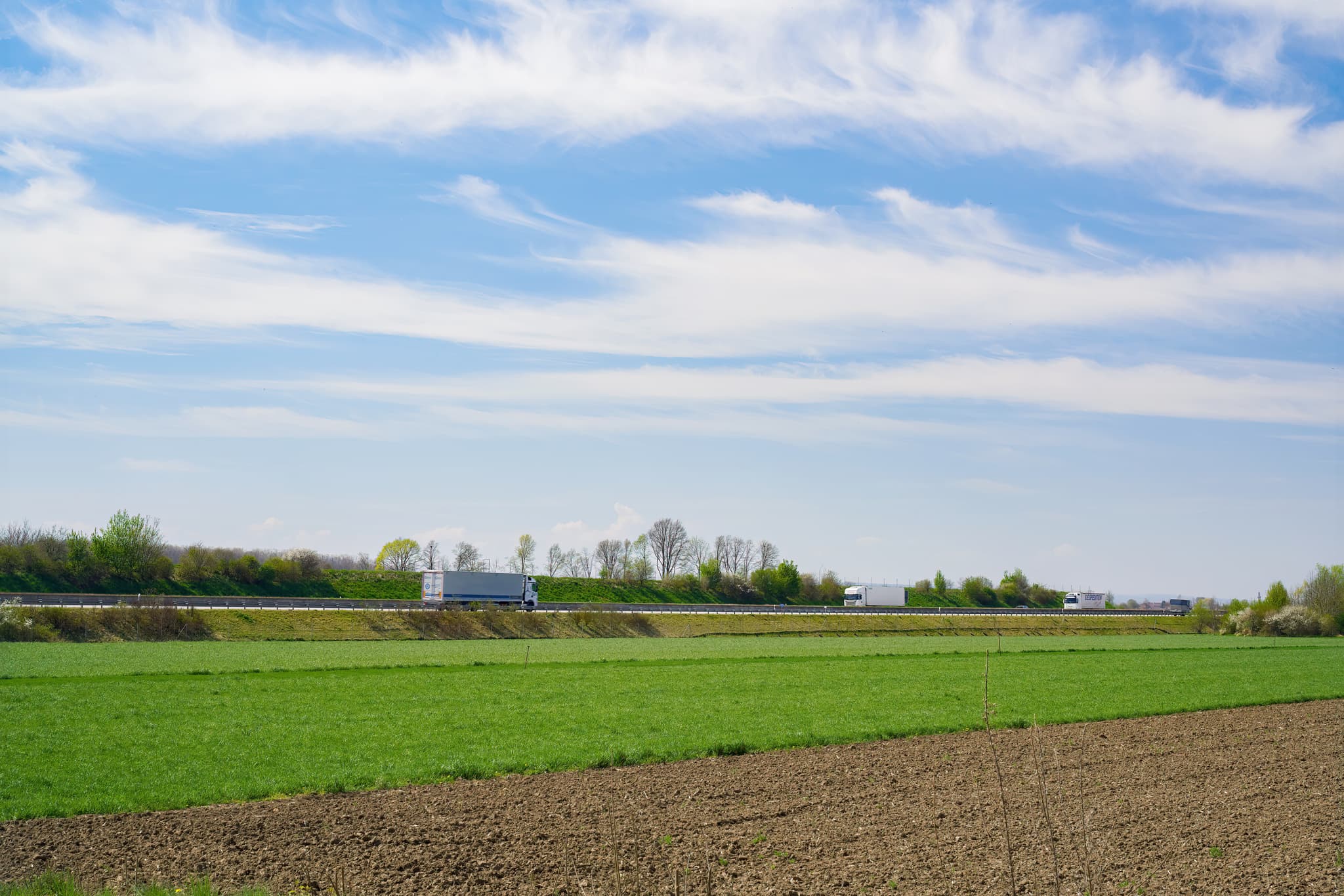 Stegmühle A94, Mühldorf am Inn, Oberbayern, Inn-Salzach - Landschaft um Stegmühle mit A94, Mühldorf am Inn. Grüne Felder, Acker. Autobahn A94 mit LKWs. Landkreis Mühldorf am Inn, Oberbayern. Weiter Himmel, Bäume.