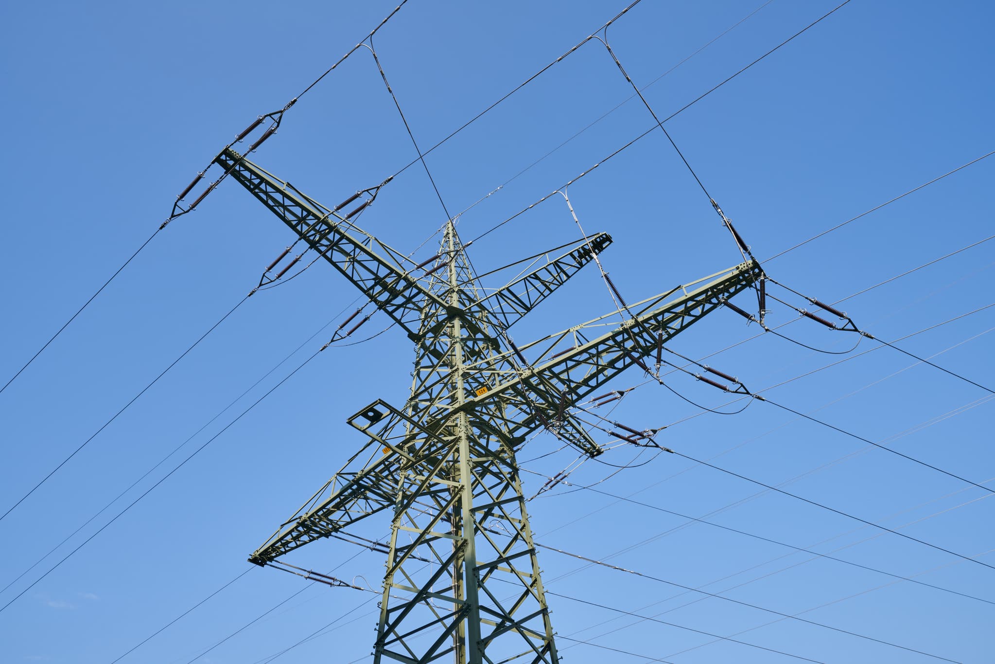 Strommasten Badhöring, Altötting, Oberbayern - Ein hoher Strommast im Ortsteil Badhöring, Gemeinde Mehring, Landkreis Altötting in Oberbayern, Region Inn-Salzach, Deutschland, unter blauem Himmel.