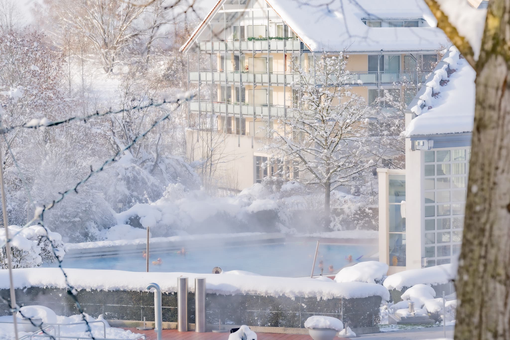Therme Kurpark Winter, Bad Griesbach, Passau - Winterliche Ansicht der Therme in Bad Griesbach, Passau, Niederbayern. Das Bild zeigt das Außenbecken im Schnee, umgebende Gebäuden und verschneiter Landschaft.