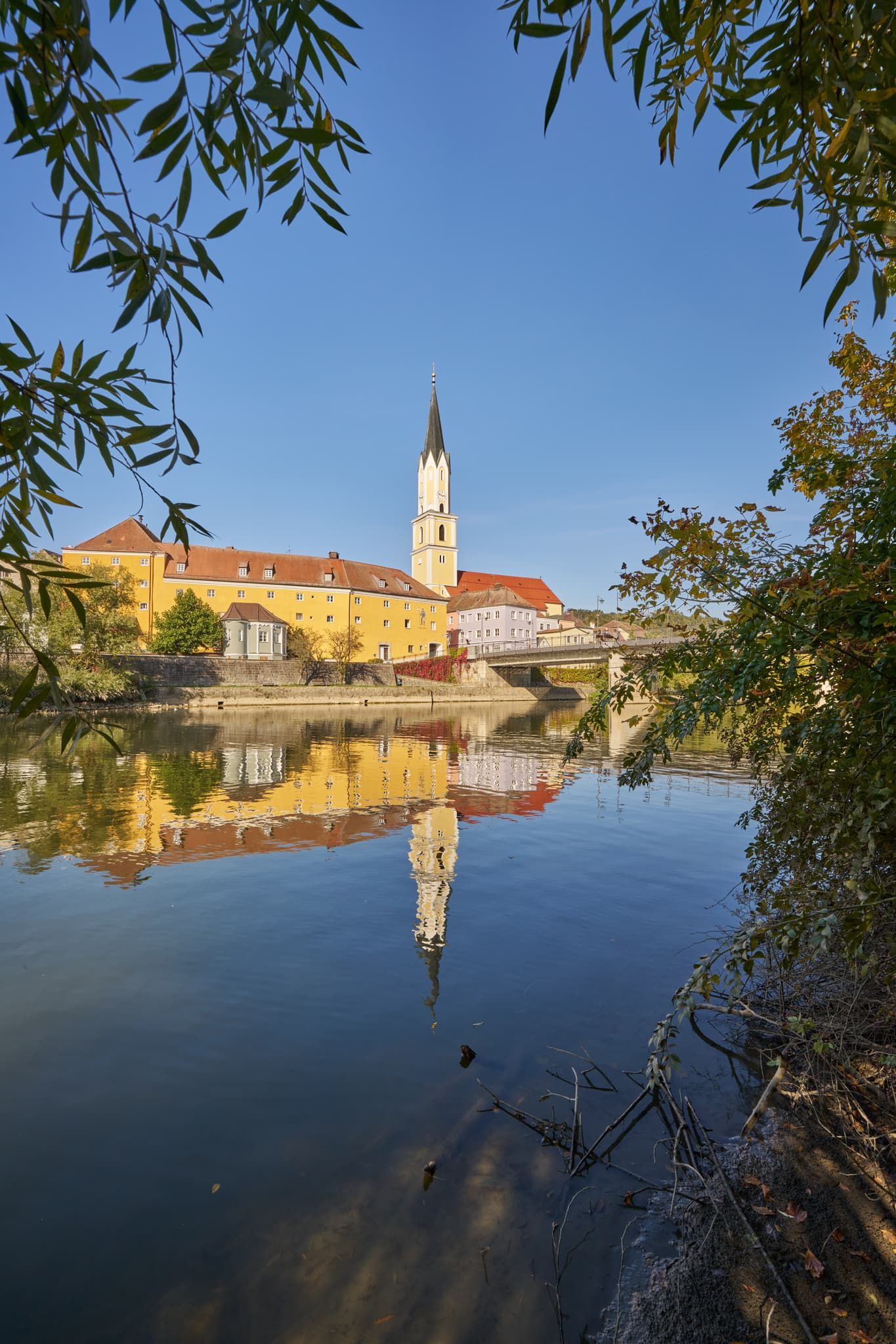 Vils Stadtansicht, Vilshofen, Passau, Niederbayern - Stadtansicht Vilshofen an der Vils, Landkreis Passau, Niederbayern. Historische Gebäude, Kirchturm und Brücke spiegeln sich im Fluss. Donau-Wald, Deutschland.
