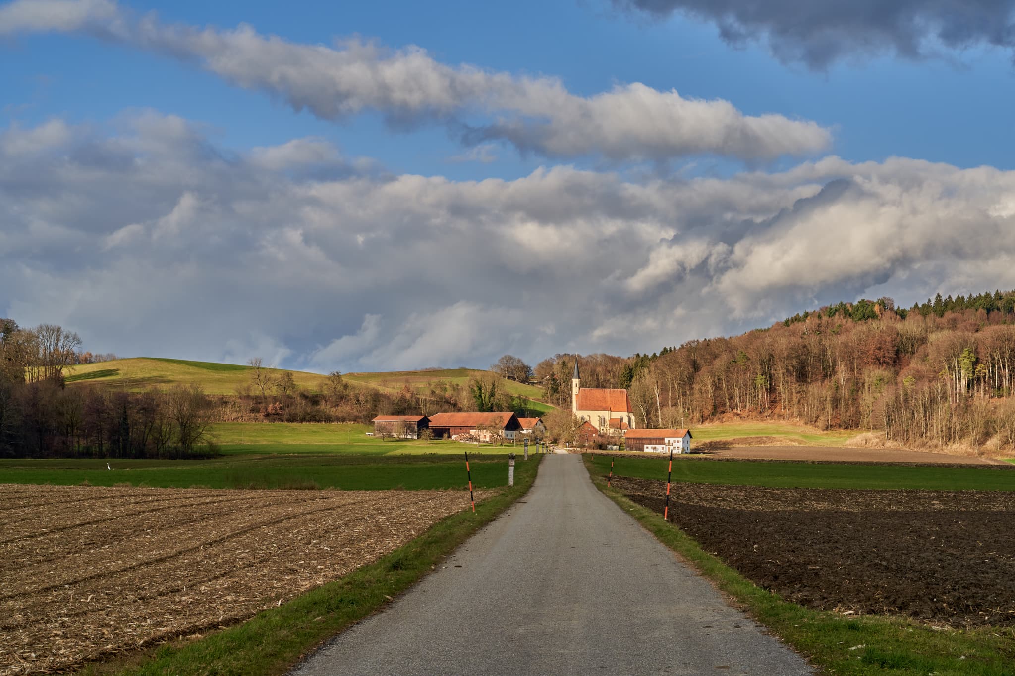 Wallfahrtskirche St. Anna, Kreuzweg Ering, Rottal-Inn - Wallfahrtskirche St. Anna, Ering, Rottal-Inn, Niederbayern, Holzland, Deutschland. Weg durch Felder, umgeben von Hügeln und Wald unter bewölktem Himmel.