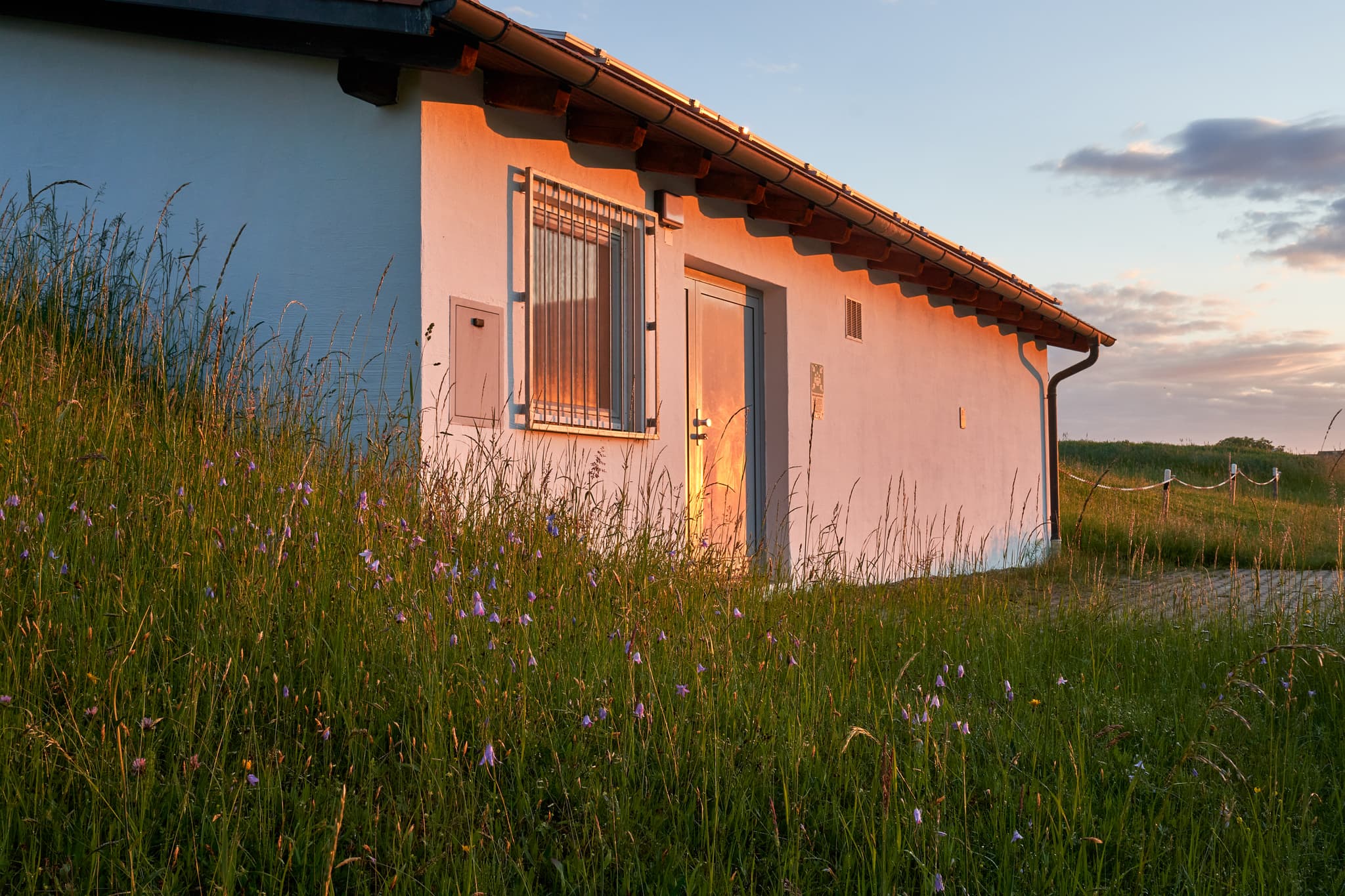 Wasserwerk Hoheneck, Reischach, Altötting, Oberbayern - Wasserwerk in Hoheneck, Reischach, Altötting, Oberbayern, Region Inn-Salzach, Deutschland.  Es ist ein kleines Gebäude inmitten einer Wiese bei Sonnenuntergang.