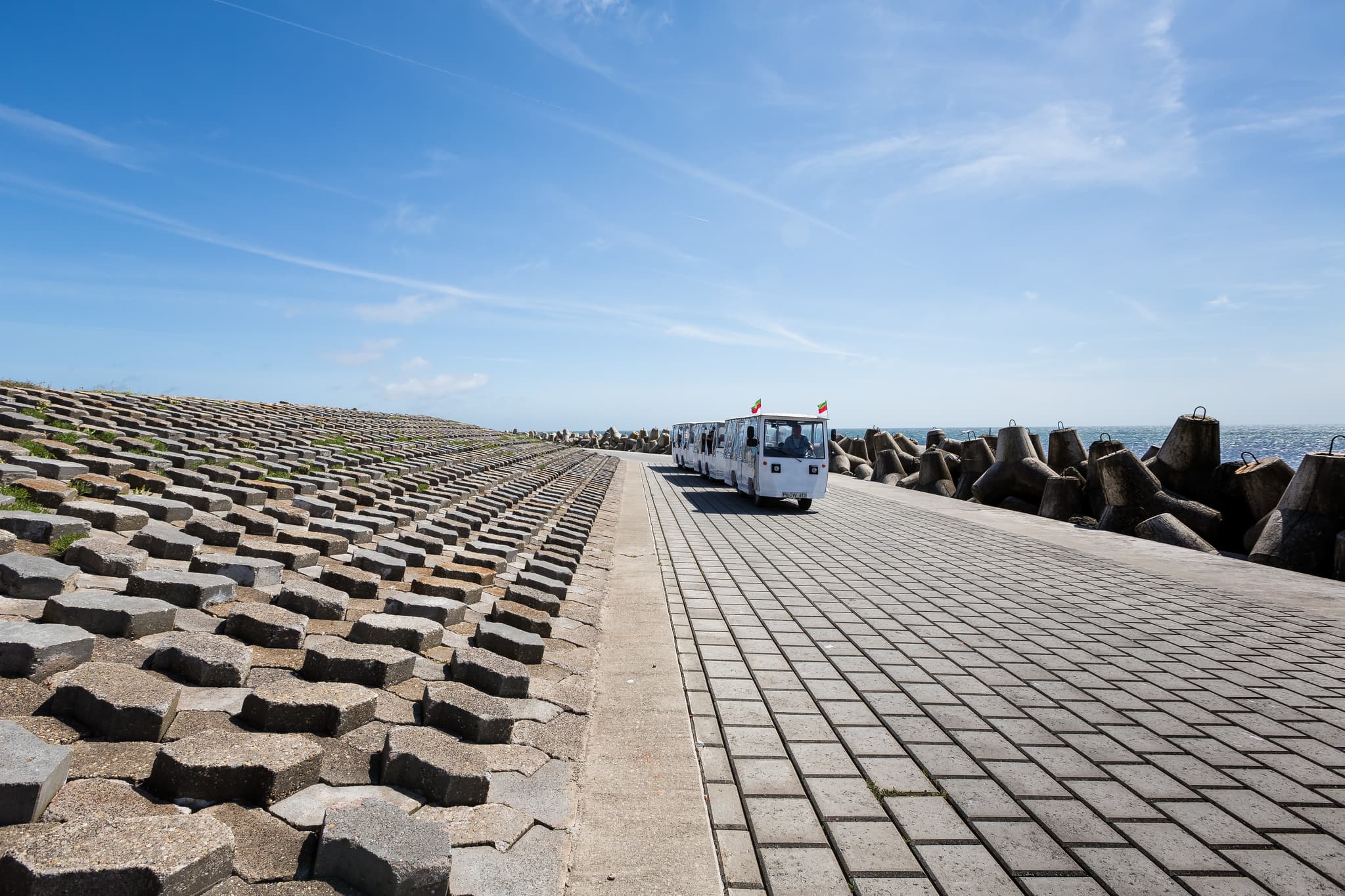 Wellenbrecher, Helgoland, Pinneberg, Schleswig-Holstein - Fahrzeug und Wellenbrecher auf Helgoland, Landkreis Pinneberg, Schleswig-Holstein. Prägnante Küstenlandschaft an der Nordseeküste Deutschlands. Blauer Himmel.
