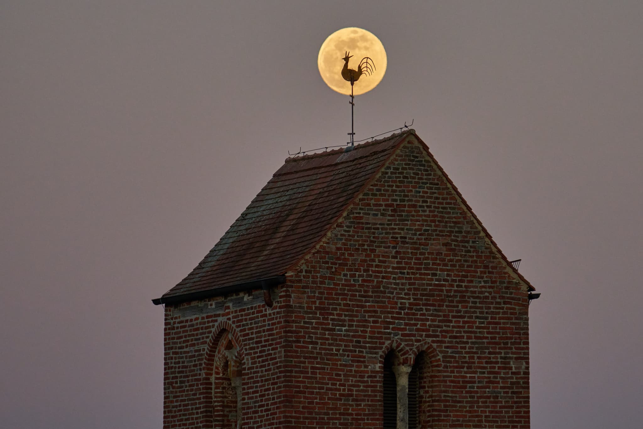 Wetterhahn vor Vollmond auf dem Kirchturm in Gehersdorf - Der Kirchturm von Gehersdorf, Zeilarn, Rottal-Inn, Niederbayern, zeigt sich mit dem Mond direkt hinter dem Wetterhahn.