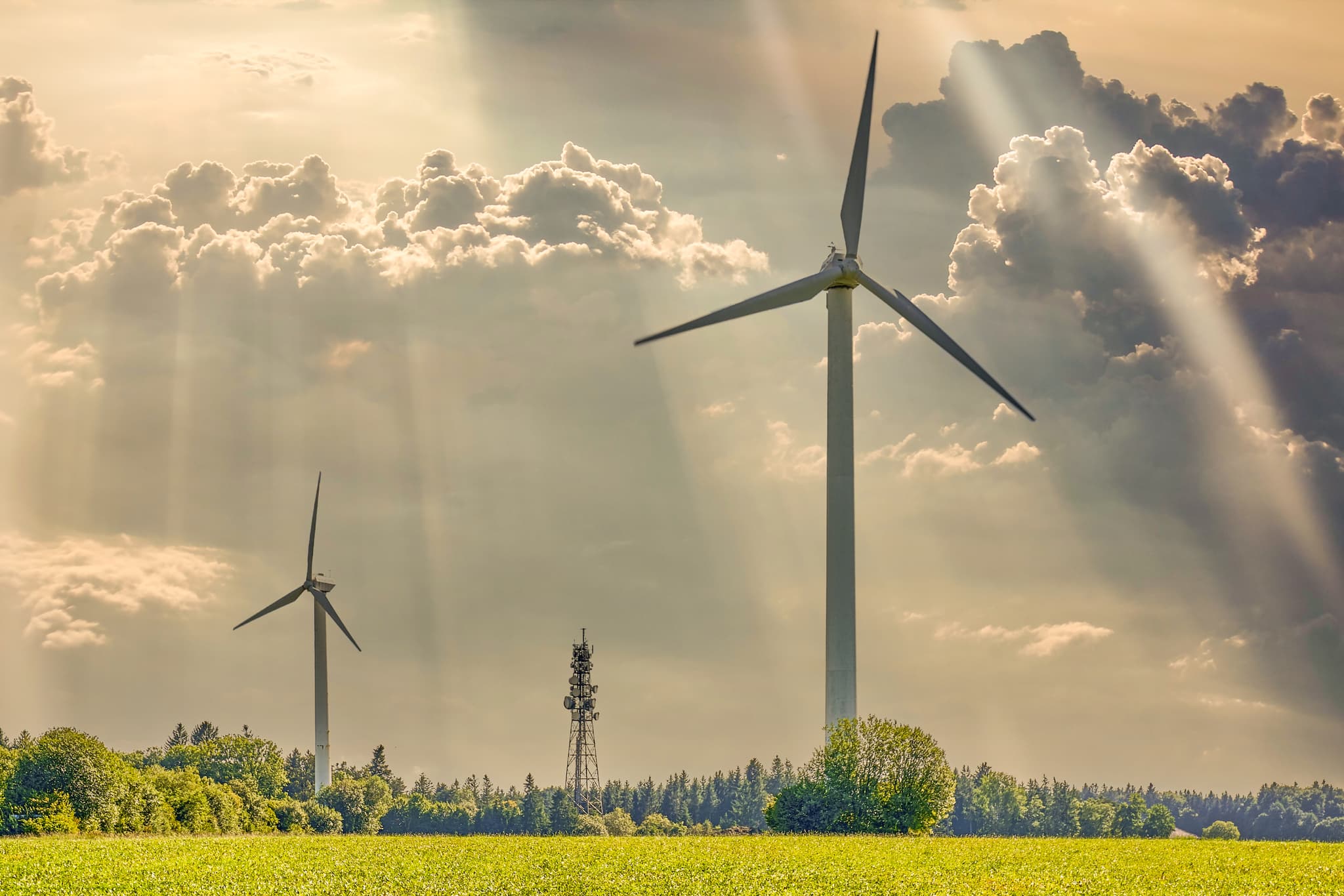 Windräder in Schnaitsee, Landkreis Traunstein, Oberbayern - Zwei Windräder auf grünem Feld bei Schnaitsee, Chiemgau, Landkreis Traunstein. Oberbayern, Deutschland. Sonnenstrahlen durchbrechen die Wolken.